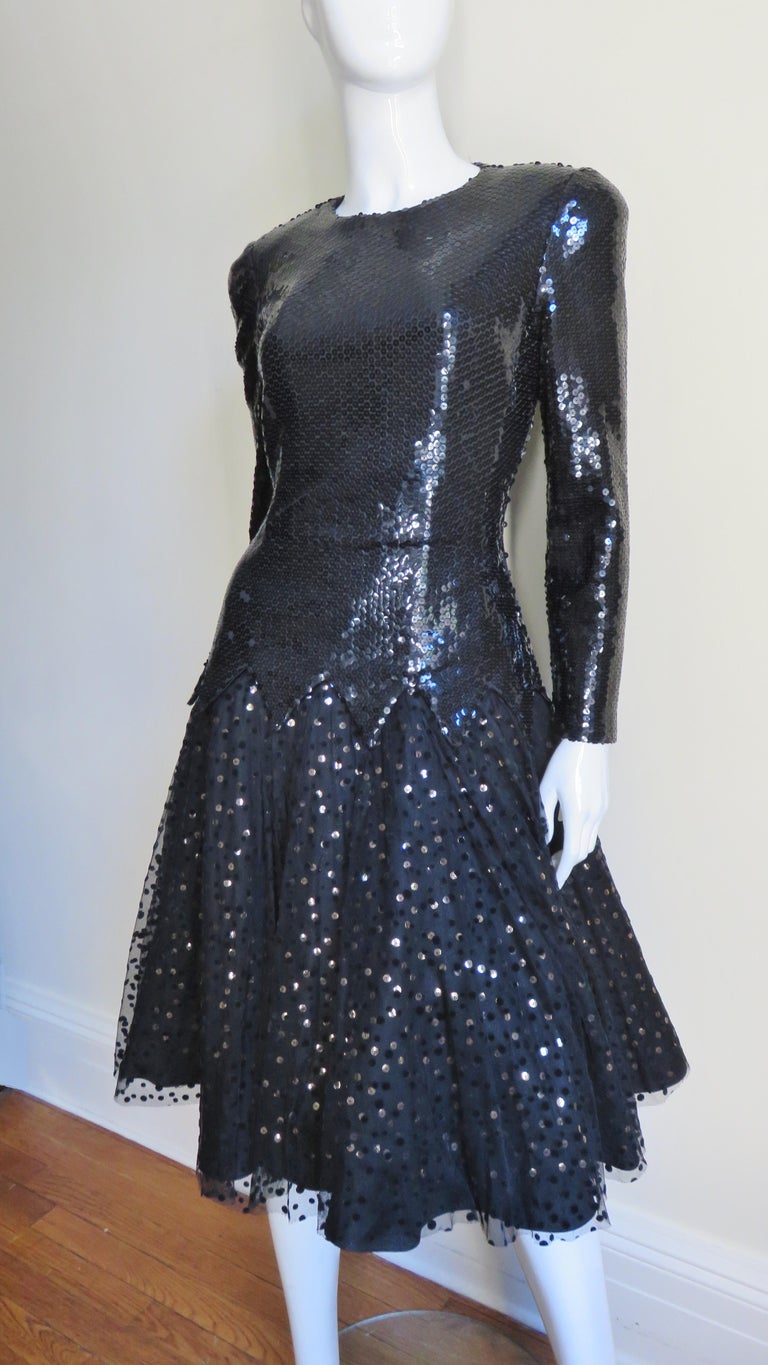 A gorgeous black sequin and tulle dress from Mignon. The bodice has long sleeves, lightly padded shoulders and a drop waist with points all covered in black sequins. The full skirt is comprised of multilayers- 2 layers of net, the top layer is