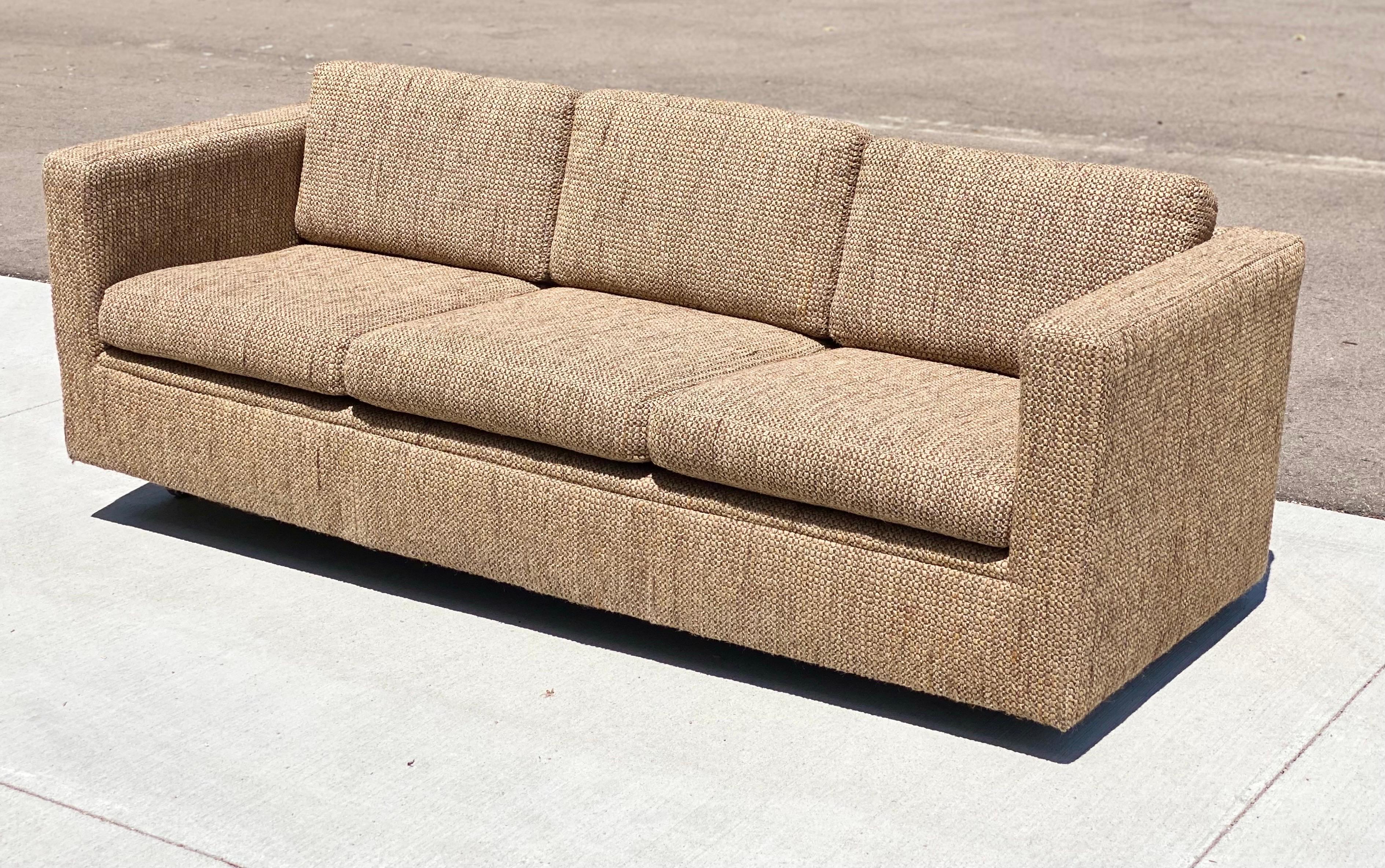 We are very pleased to offer a chic, tuxedo sofa by Milo Baughman for Thayer Coggin, circa the 1980s. This sofa showcases a wraparound frame and loose cushions upholstered in a wool brown fabric. The sofa sits on four short legs. Marked on the