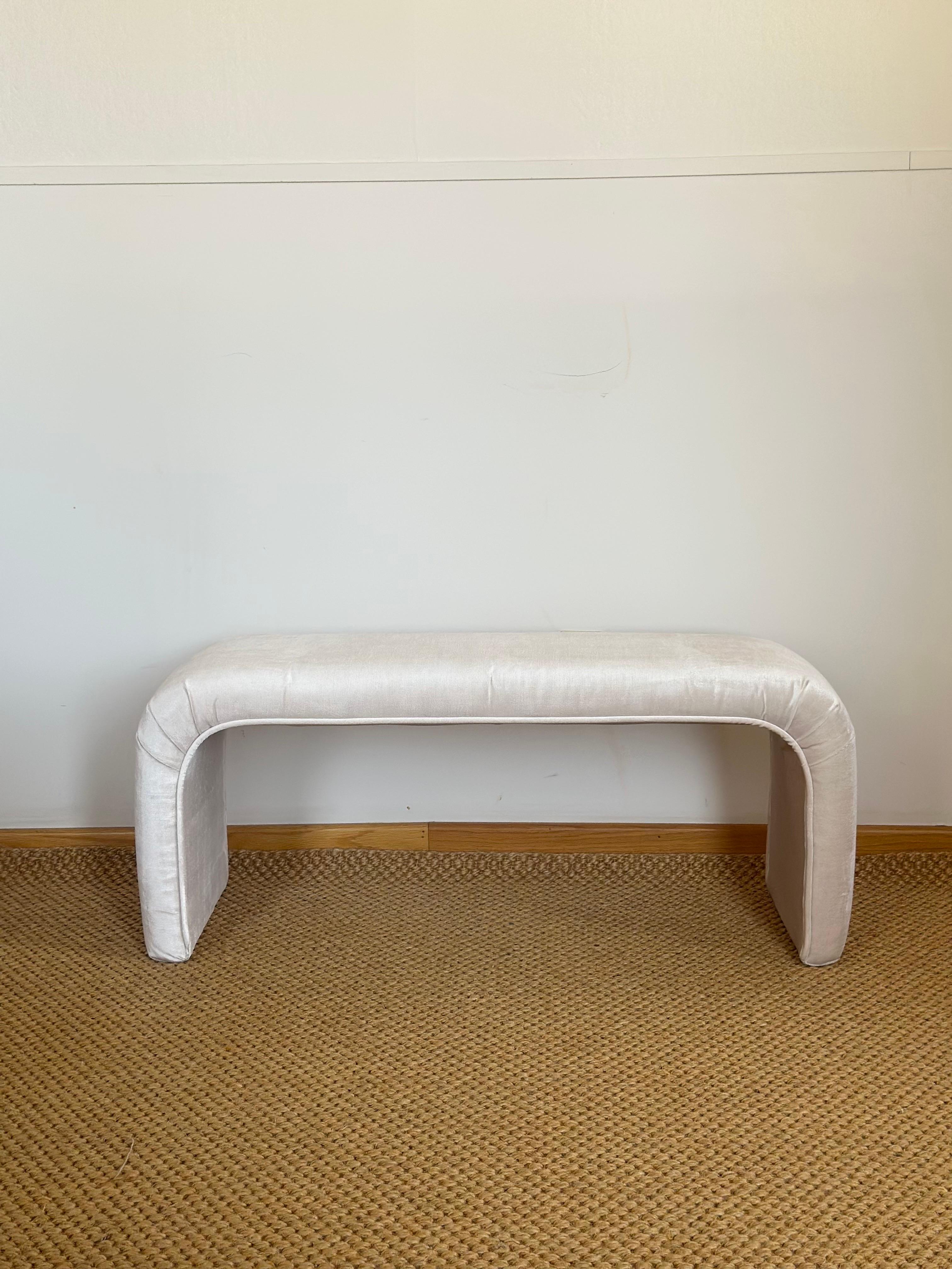 Nos complace ofrecerte un banco de cascada minimalista de los años 80 con una silueta suave y escultural.  Totalmente tapizado en un nuevo y lustroso terciopelo de color marfil o champán, presenta una curva continua que fluye desde el asiento hasta