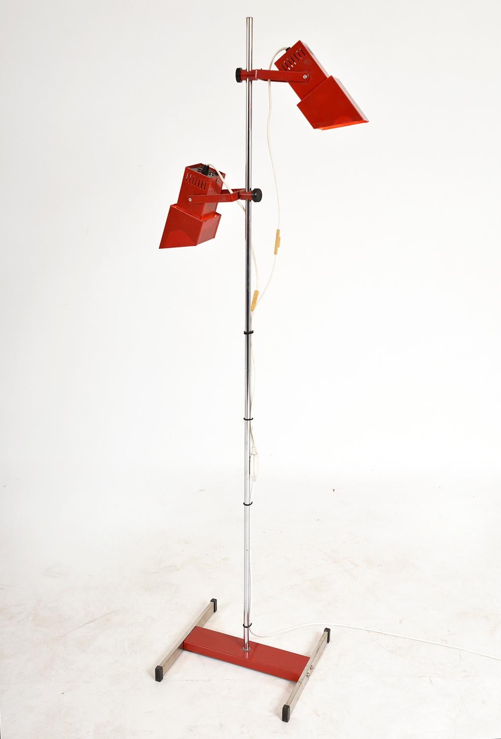 This unusual 1980s Italian floor lamp features a chromed aluminium pole stood on a chromed i-beam style base, with twin spot square shades that can be adjusted in height and angle. The lamp is equipped with a double switch, thereby the spotlights