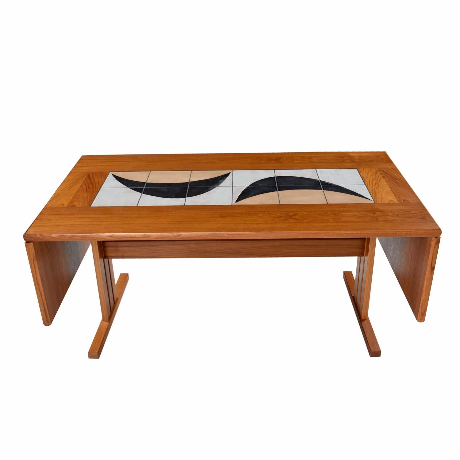 This teak dining table by Gangsø Møbler exudes style with its artful tile motif. The tiles are not purely decorative. They serve a practical purpose. Place hot or wet plates on the tile to prevent damaging your wood surface. The table is a drop leaf