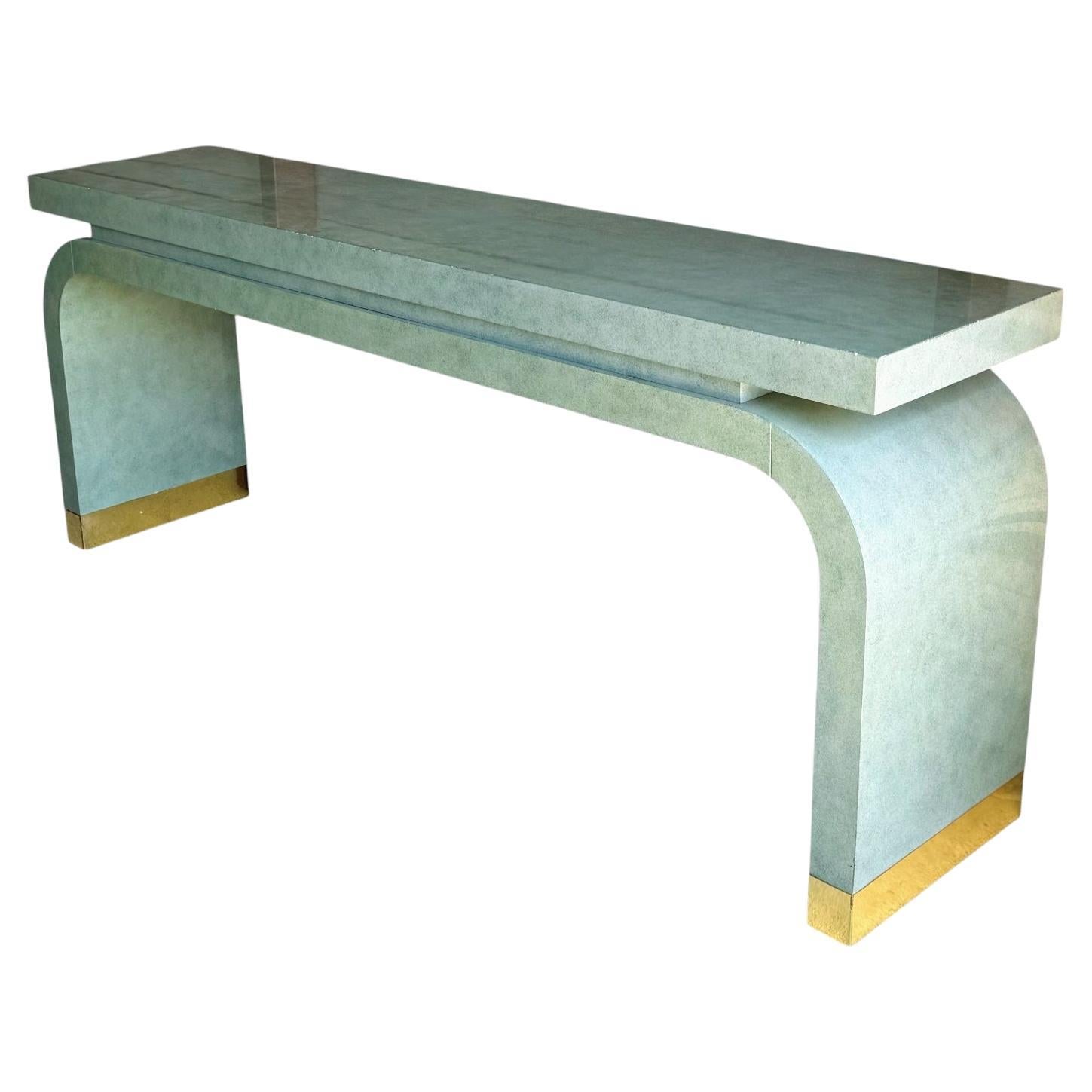 This is a large scale 1980s modern Ming style console table attributed to Italian designer Alessandro. Alessandro had a brief collaboration with Baker Furniture. It does have the Baker tag. It is a green seafoam color and has brass capped feet.