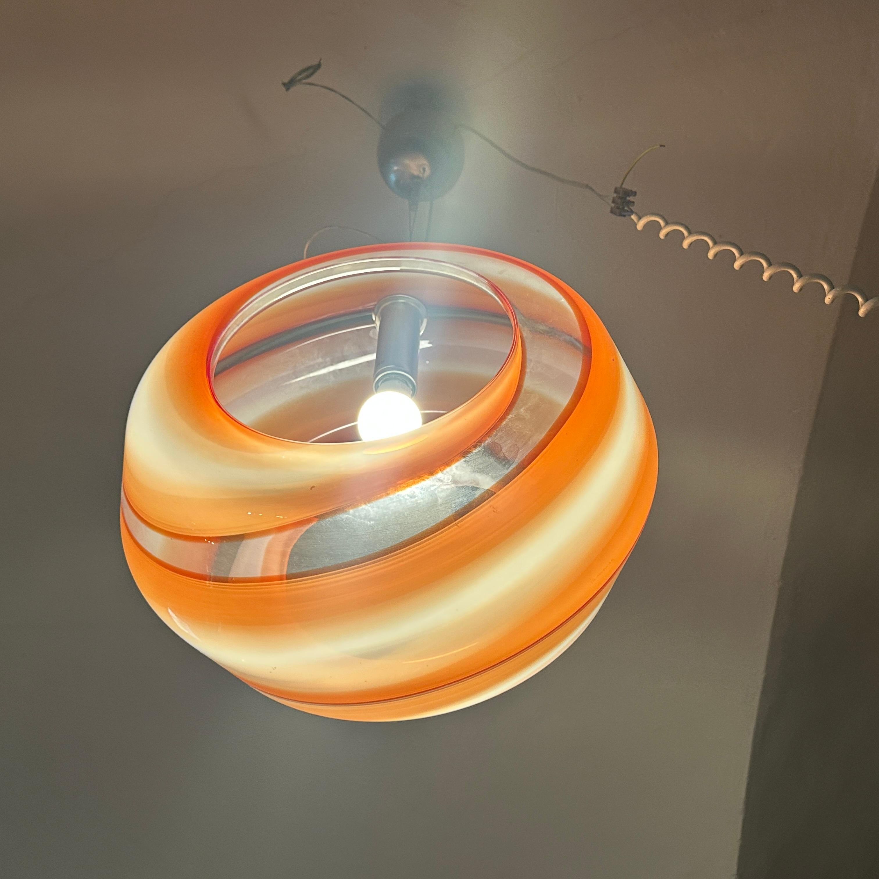 Vintage 1980s Modern Orange and White Murano Glass Pendant Lamp by La Murrina
The pendant features a mesmerizing, hand-blown Murano glass shade with a captivating swirl design. The outer layer showcases a vibrant, semi-opaque orange hue that blends