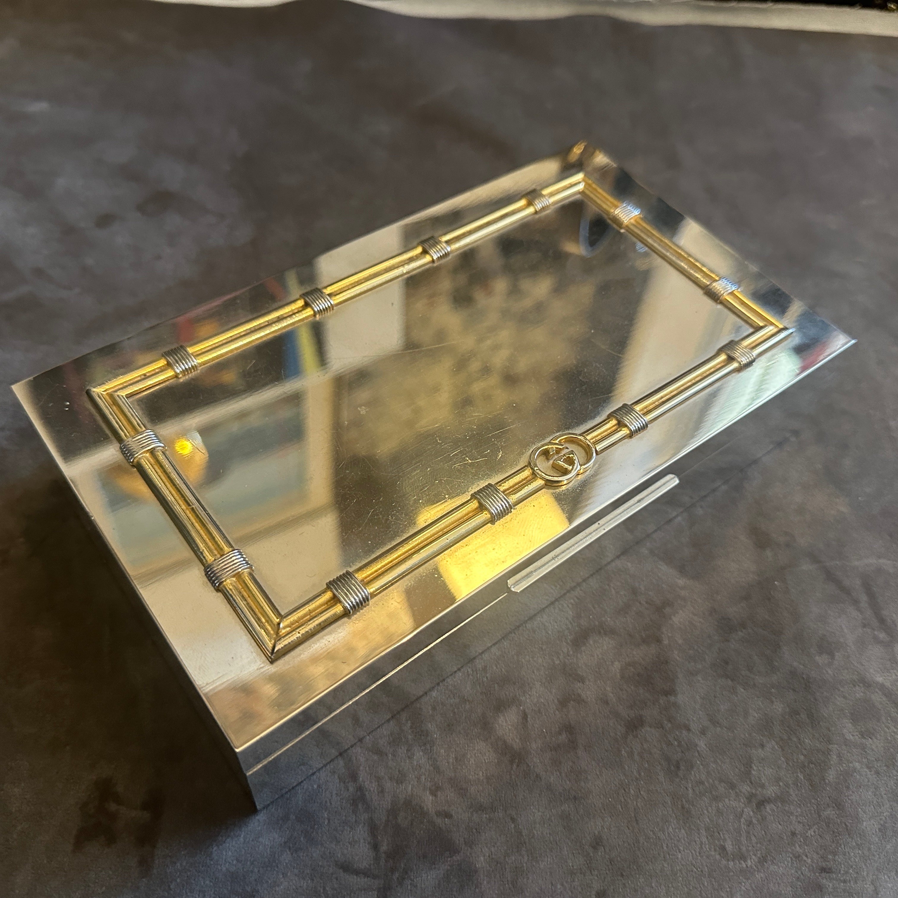 Questo è uno splendido esempio di lusso e design moderno degli anni '80, una scatola rettangolare Gucci Florence. Realizzato con un esterno argentato lucido, il cofanetto è immediatamente riconoscibile per gli squisiti dettagli in ottone sul