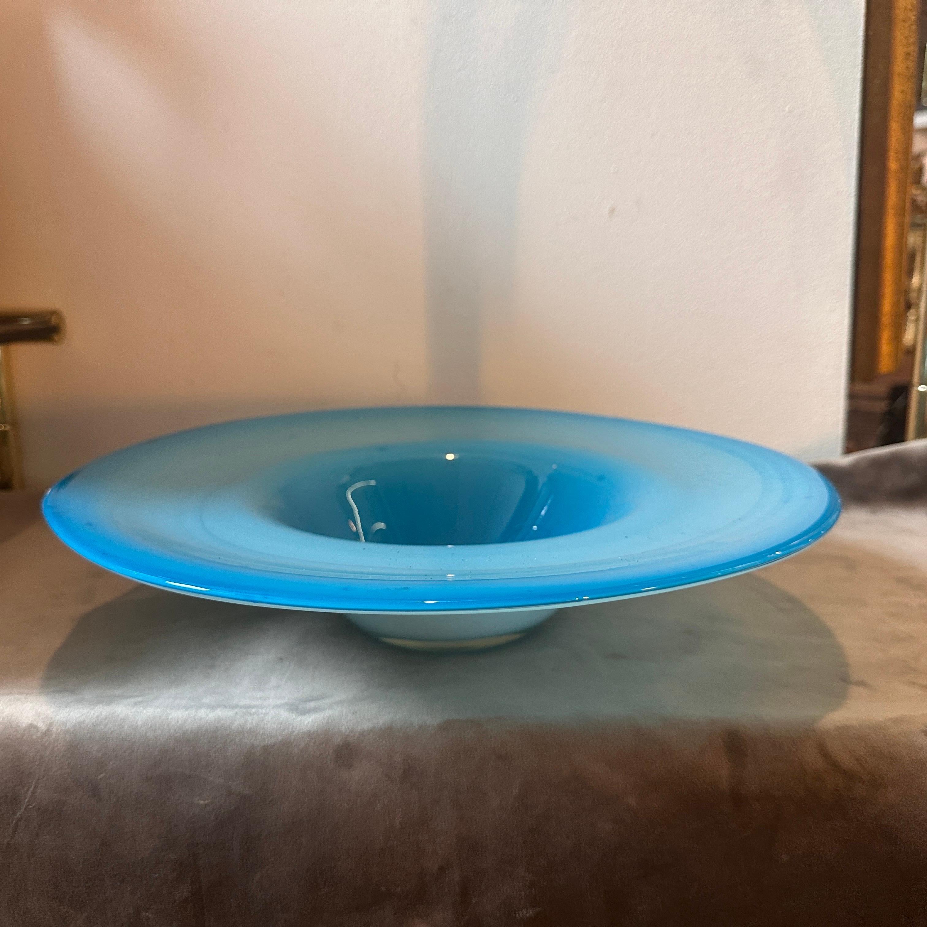 A 1980s Turquoise and White Murano Glass Centerpiece designed and manufactured in Italy in the style of Venini. This Round Centerpiece is a stunning decorative object that embodies the design sensibilities of the 1980s and showcases the renowned