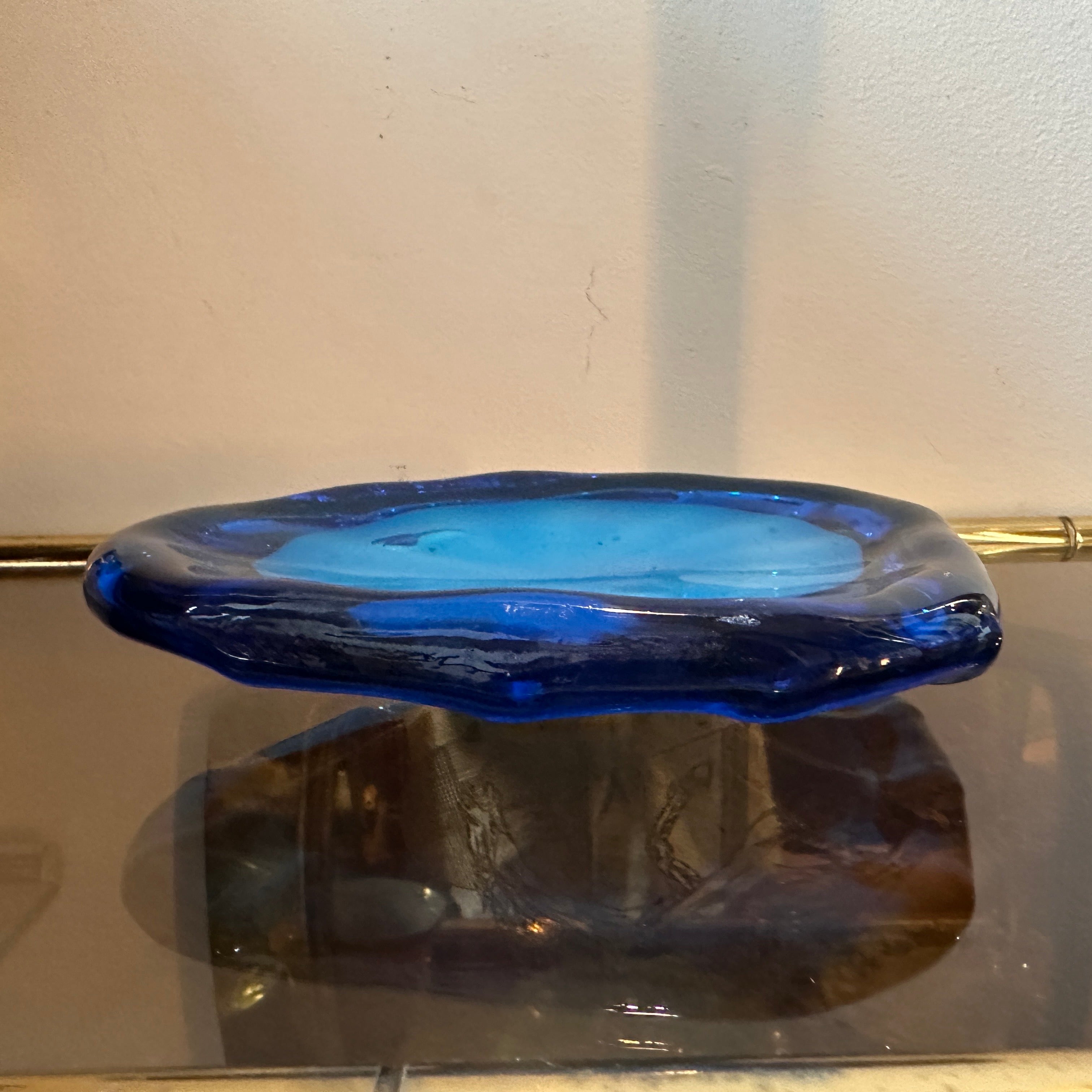 Il Vide Poche in vetro di Murano blu e turchese degli anni '80 è uno straordinario esempio di arte vetraria italiana, che fonde un design funzionale con colori vibranti ed eleganza. Realizzato in vetro di Murano, è un esempio della maestria dei