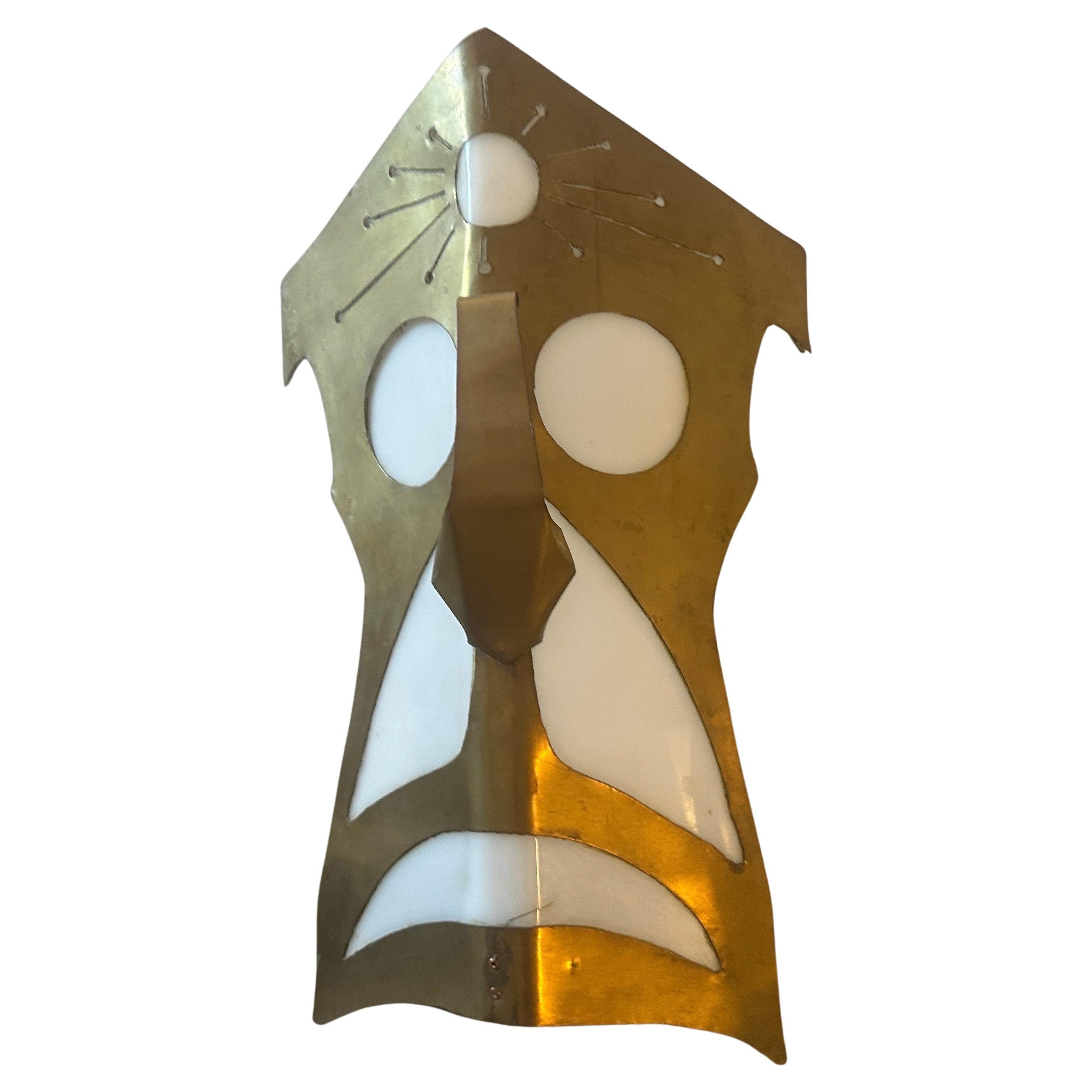 An hand-crafted brass and white plexiglass wall light depicting a tribal mask, it has been manufactured in Italy in the Eighties, brass it's in original patina, plexiglass white parts are in perfect condition and it's in working order. It's a unique