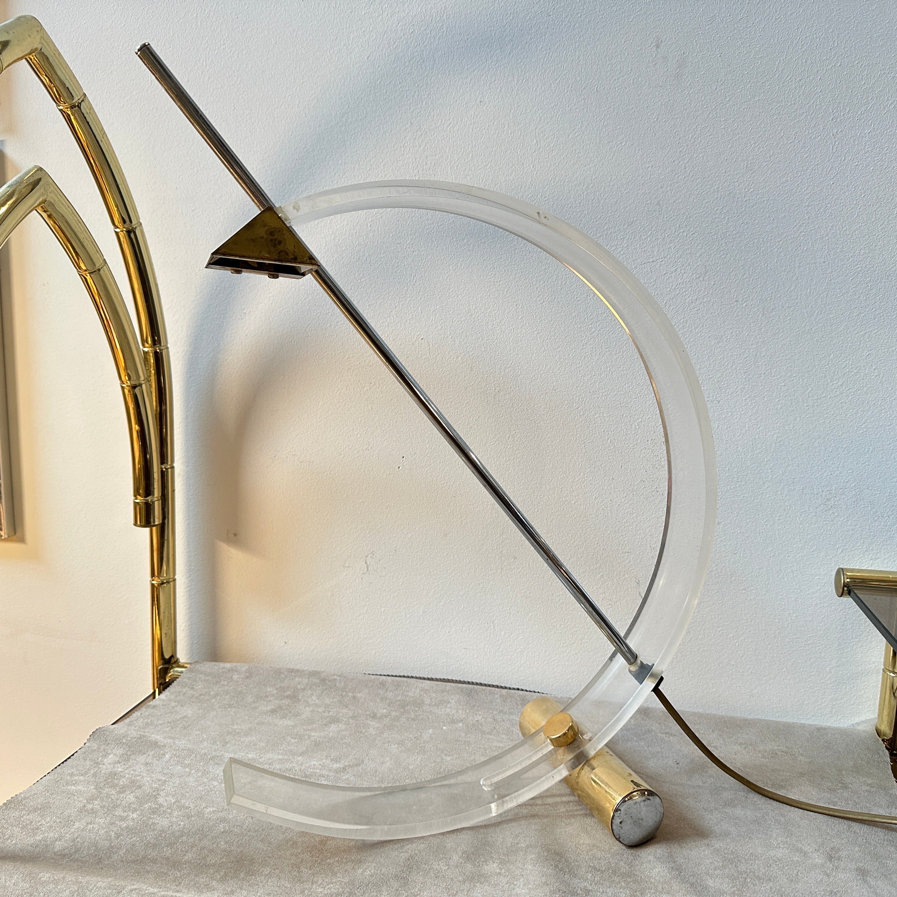 A design table lamp manufactured in Italy in the Eighties, the plexiglass arc is mounted on a brass metal base, and the halogen bulb is positioned in a metal triangle. The lamp is in original very good condition and in perfect working order. It is a
