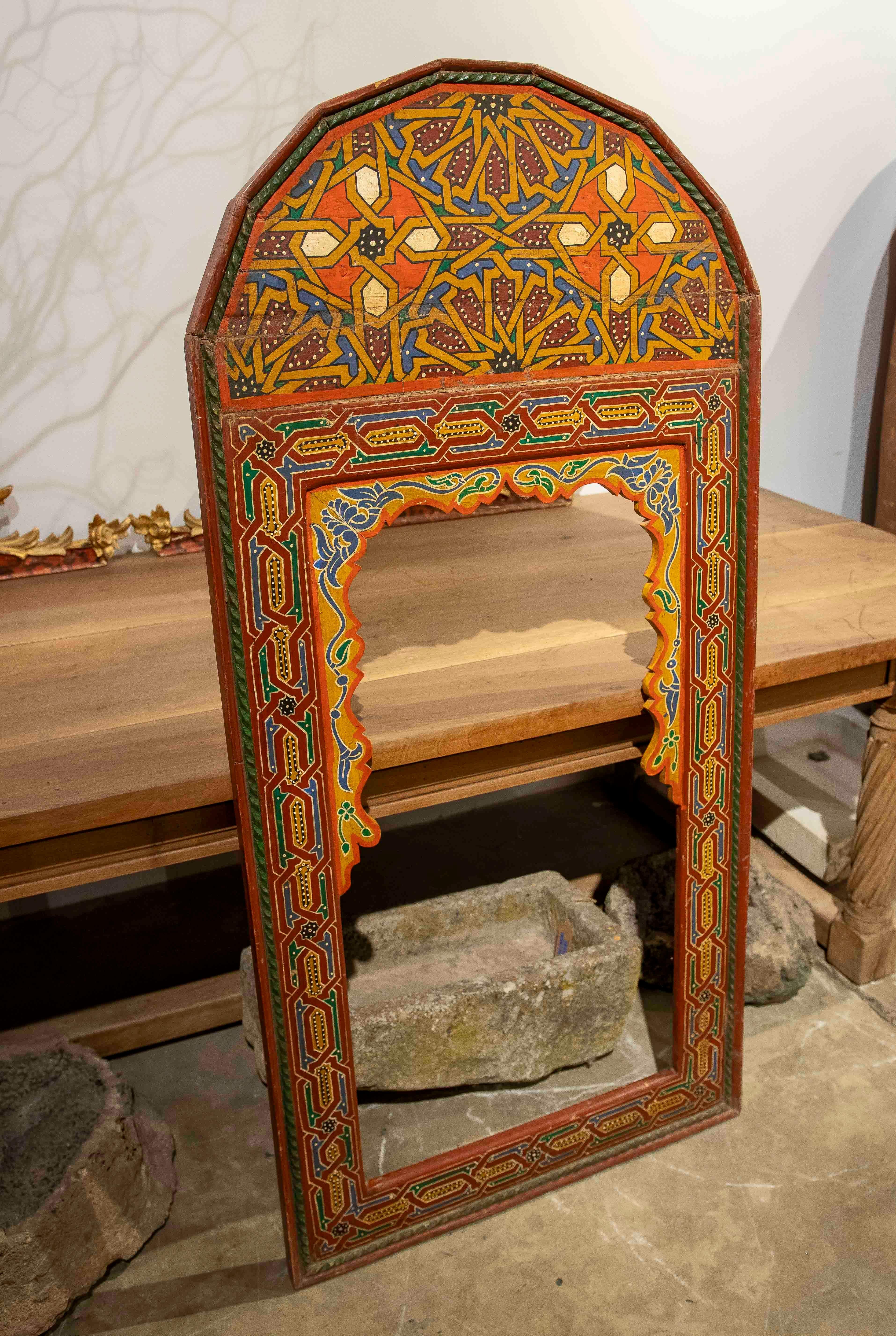Exquis miroir marocain polychrome peint à la main avec un cadre en bois orné de motifs géométriques et floraux méticuleusement travaillés. Les couleurs vives - rouges, verts, jaunes et bleus - évoquent les riches traditions artisanales de l'Afrique