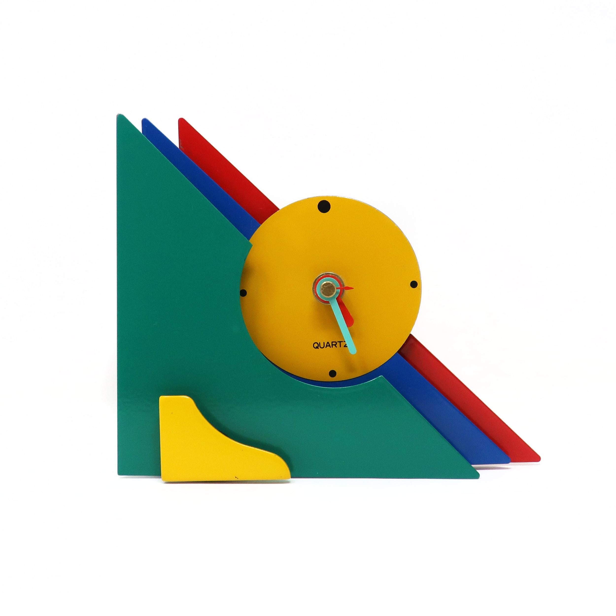 Avec une combinaison étonnante de métal émaillé rouge, bleu, vert et jaune, et des accents de lucite jaune, cette horloge postmoderne est conçue avec un design triangulaire empilé qui lui donne une rare et belle tridimensionnalité. Ses couleurs