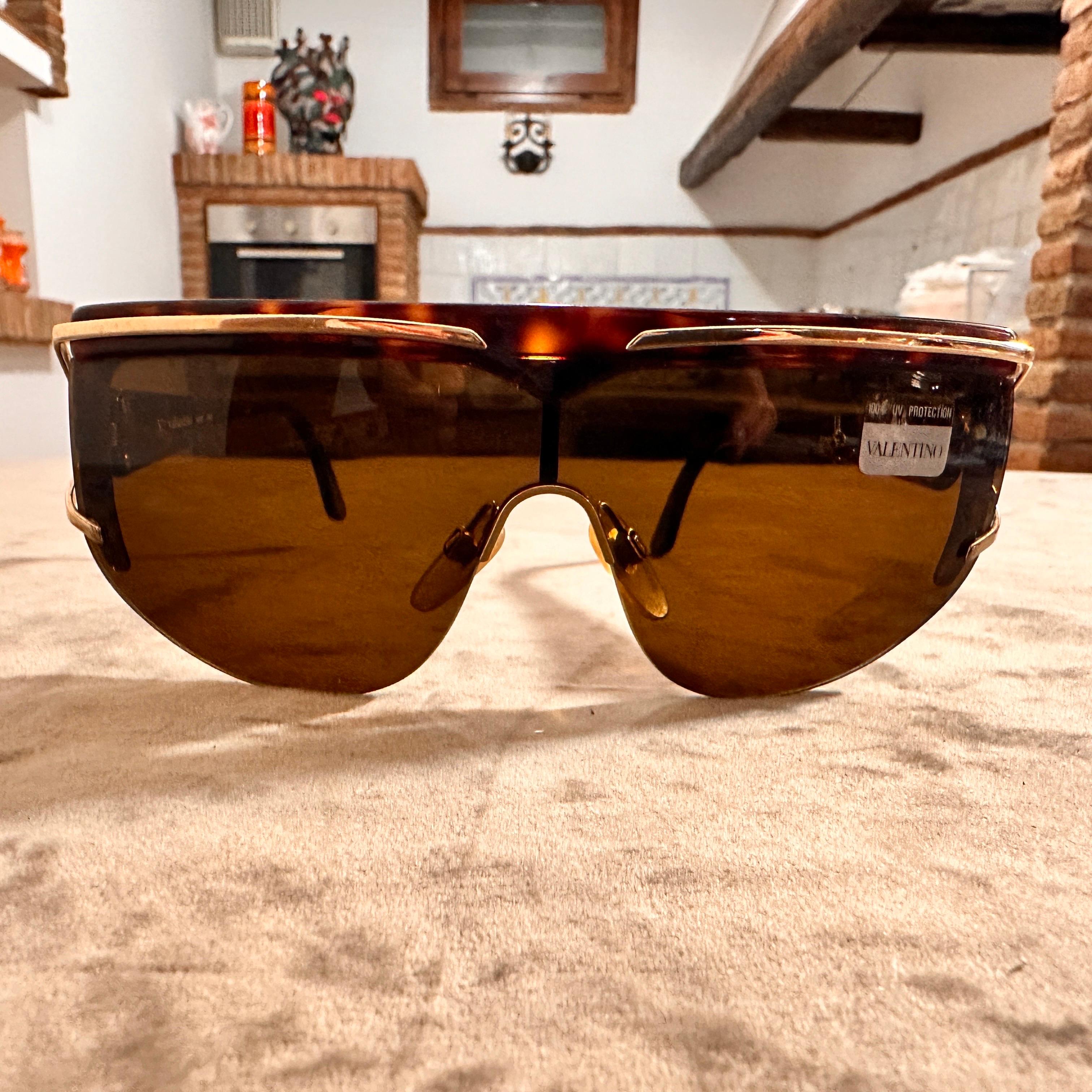 These distinctive Valentino sunglasses are a bold, modern take on eyewear, designed for those who want to make a stylish statement. Crafted with a sleek, shield-style design, these sunglasses cover the eyes seamlessly, offering not only full