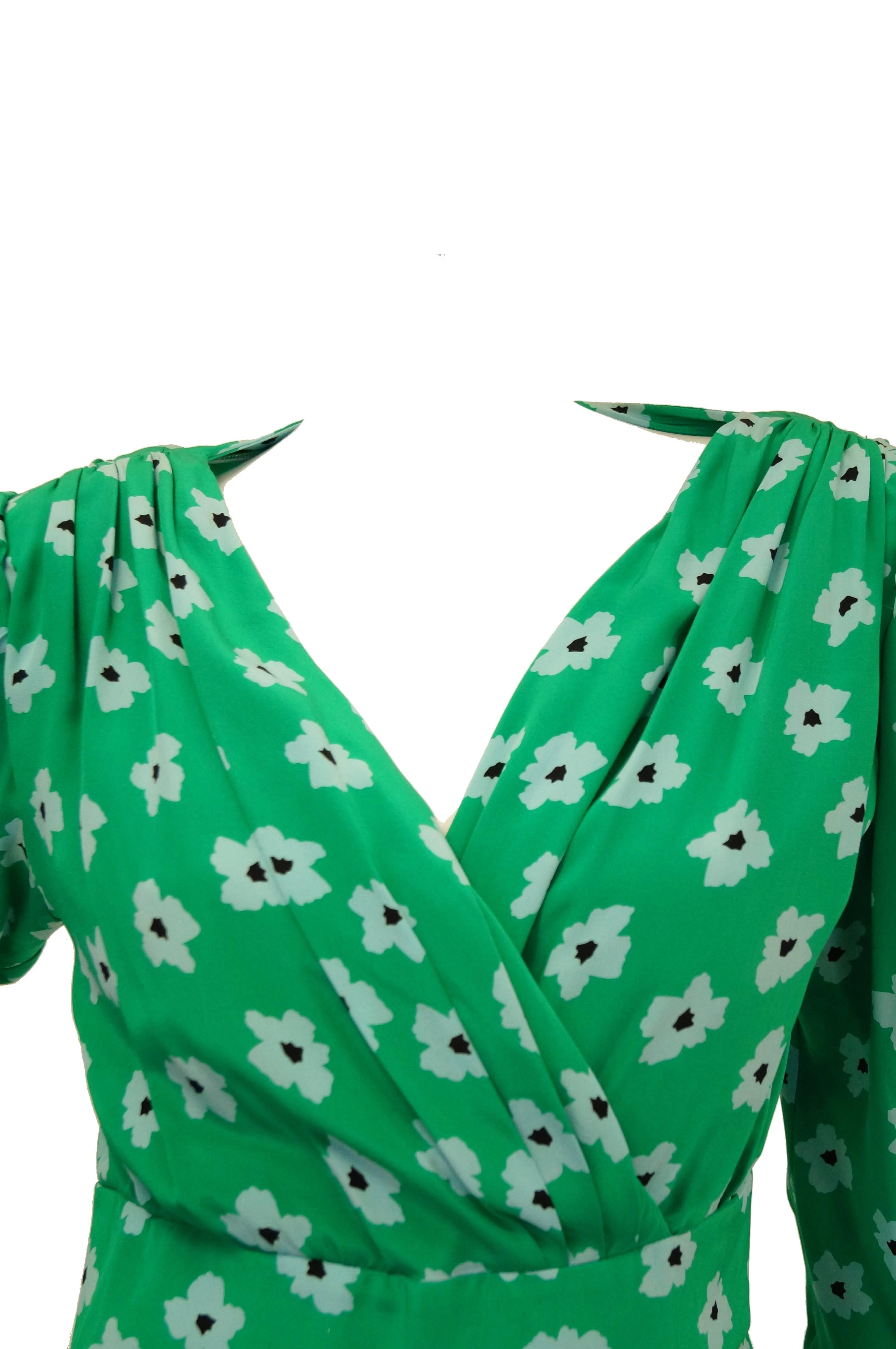 1980s green with white flowers silk dress by Nina Ricci. The dress is knee length with 3/4 length sleeves, and a V - neck surpliced neckline created by the faux wrap drape closure of the dress. The dress has structured shoulders and a tulip skirt.