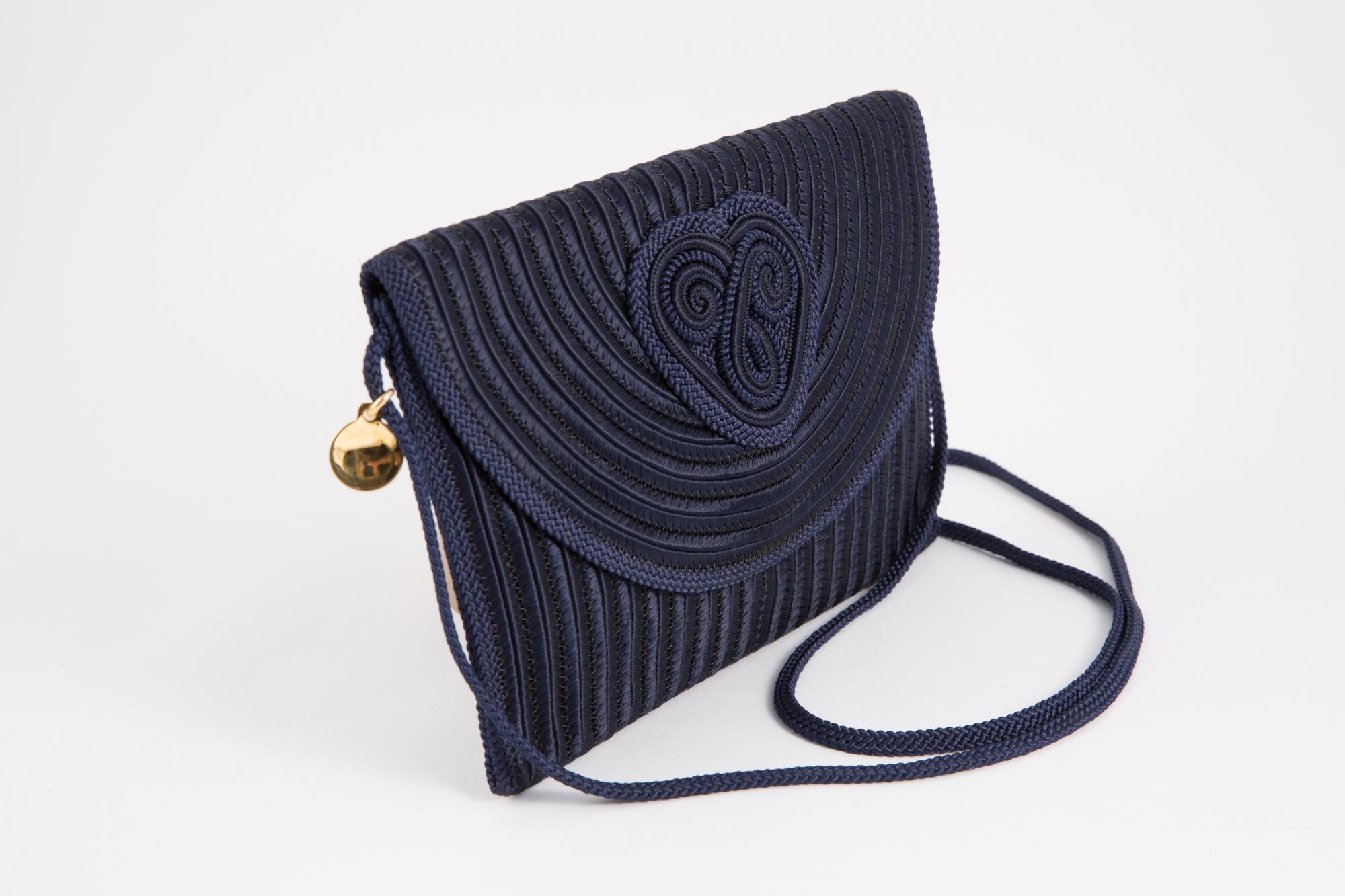 Nina Ricci 1980s silk navy braided bag featuring a front flap with a braided heart, a front under flap snap, a long braided shoulder handle (41.3in. (105cm)) with a gold tone logo medal on.
In excellent vintage condition. Made in