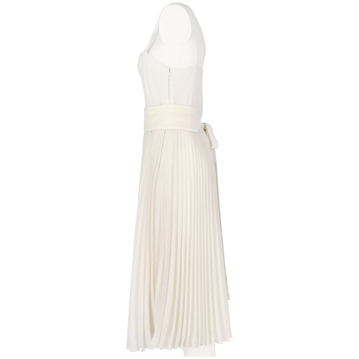 Nina Ricci Boutique white wedding dress. It features a pleated skirt with waistband and very thin straps. Lined and finely hand-finished. Lateral zip closure. Spare buttons included. The items is vintage, it was produced in the 80s and is in