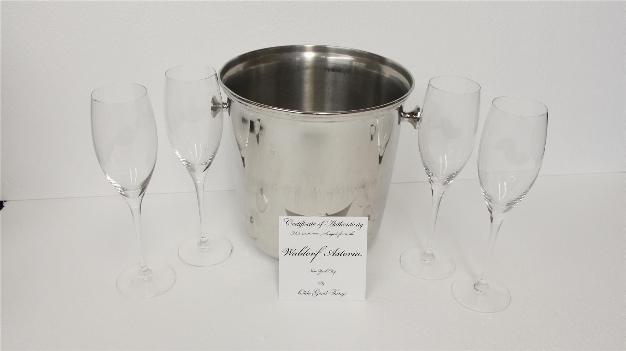 Five-piece bucket and clear glass wine set salvaged from the Waldorf Astoria. A Waldorf authenticity card is included with your purchase. Set includes one 1980s bucket and four wine glasses. The dimensions are; glasses 10 in. height x 2.75 in.