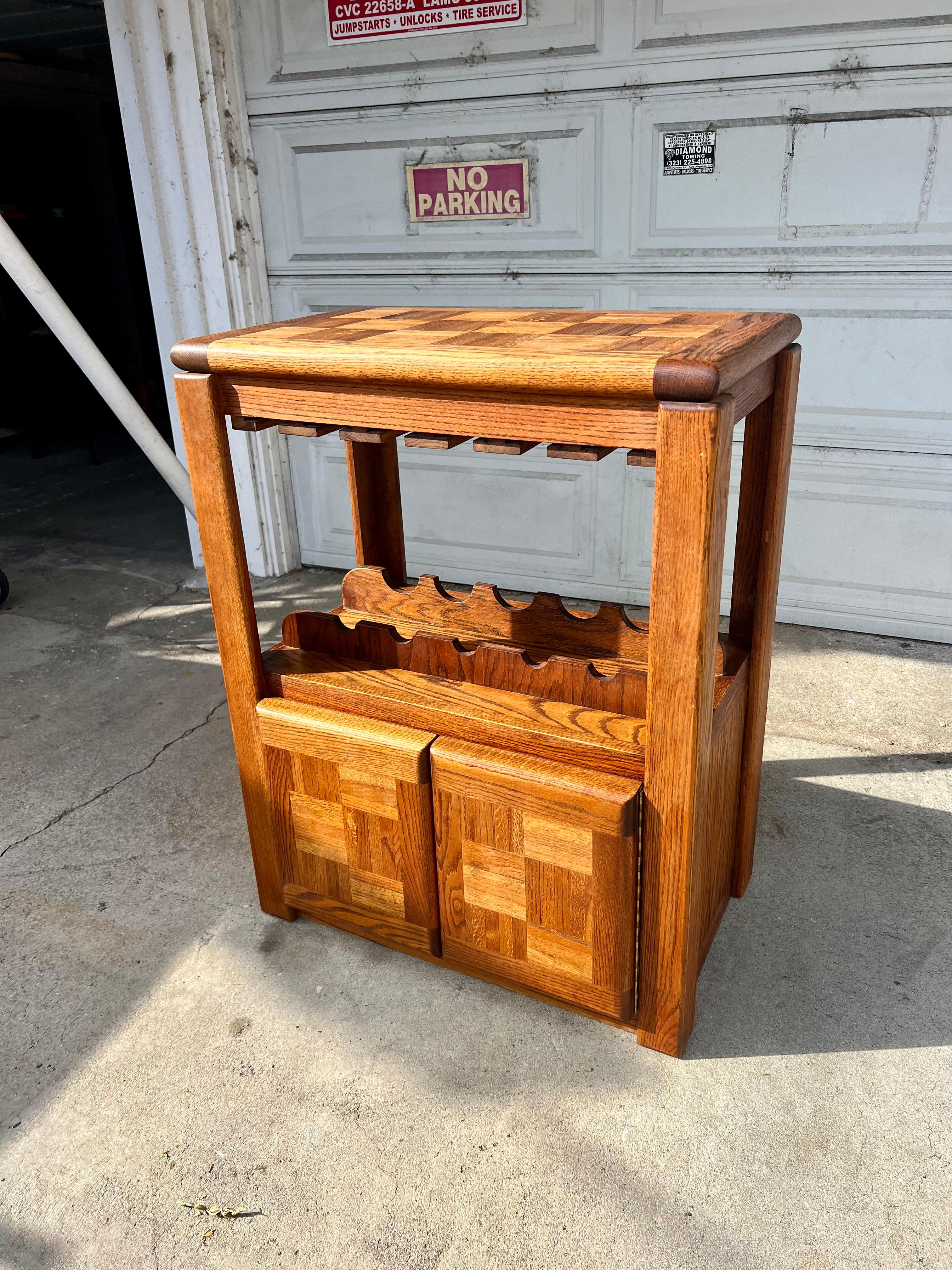 This vintage oak dry bar cabinet features exquisite parquet detailing on it’s top and doors. Superb craftmanship adds a wine rack with space for 5 bottles and multiple stemmed glassware. This chunky gem has both style and function and is the perfect