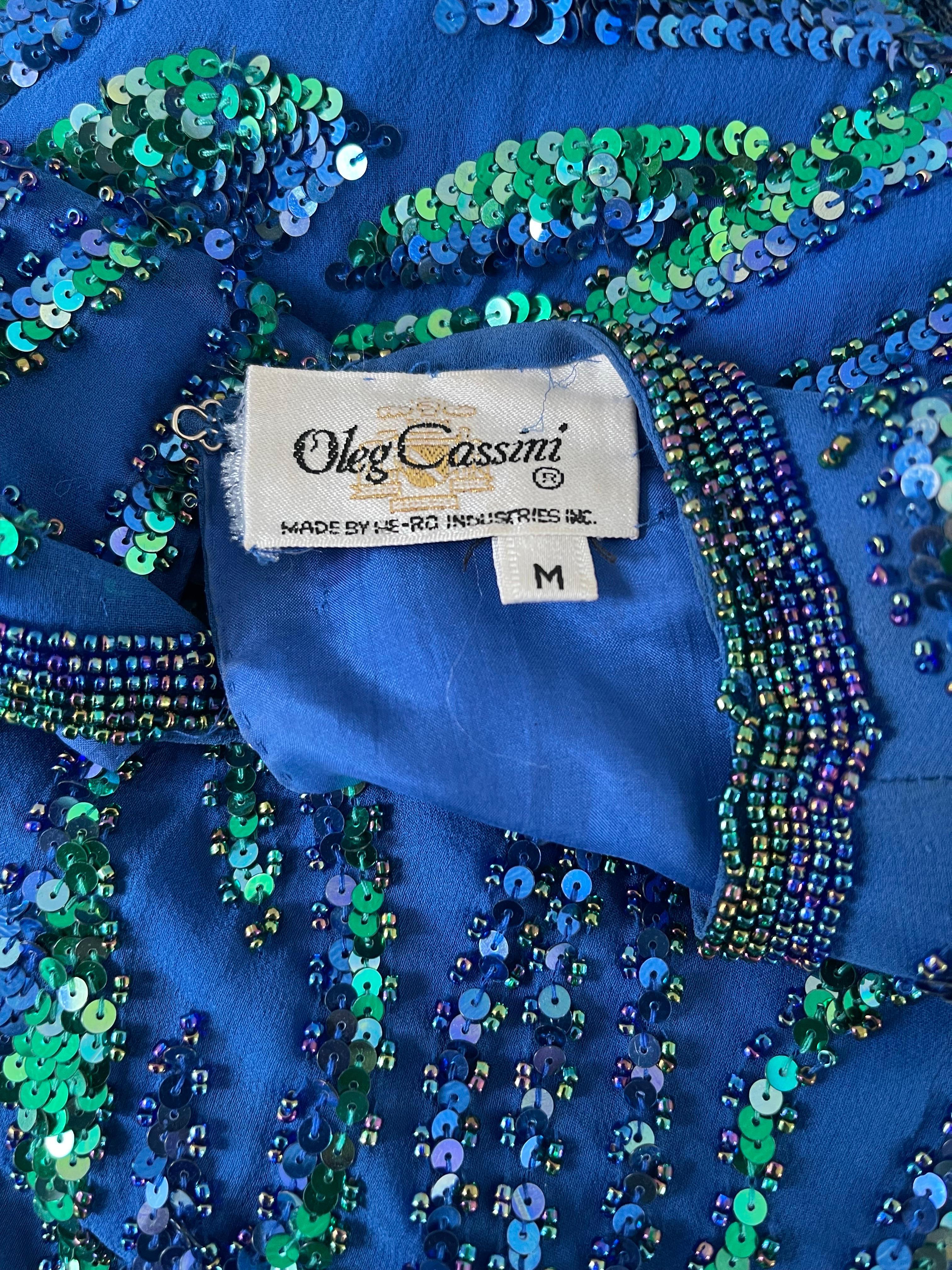 Beautiful 1980s OLEG CASSINI blue and green silk chiffon sequin and beaded long sleeve top ! Peacock colors — Thousands of hand-sewn sequins and beads throughout the entire shirt. Hidden zipper up the side. Hidden snaps at each sleeve cuff.
Can