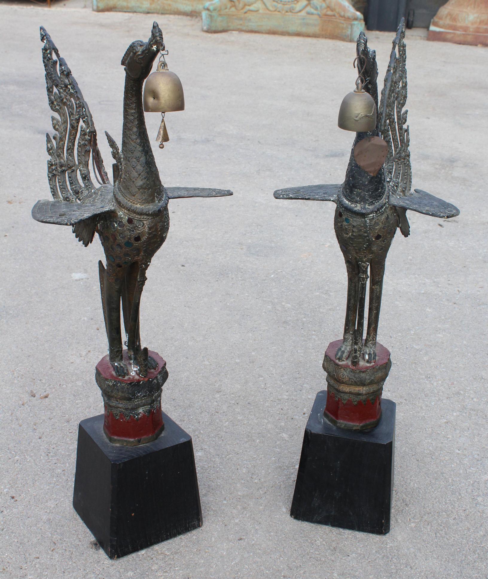 1980s pair of Asian bronze Garuda mythical Hindu birds with colored glass decorations on the wings and wooden bases.