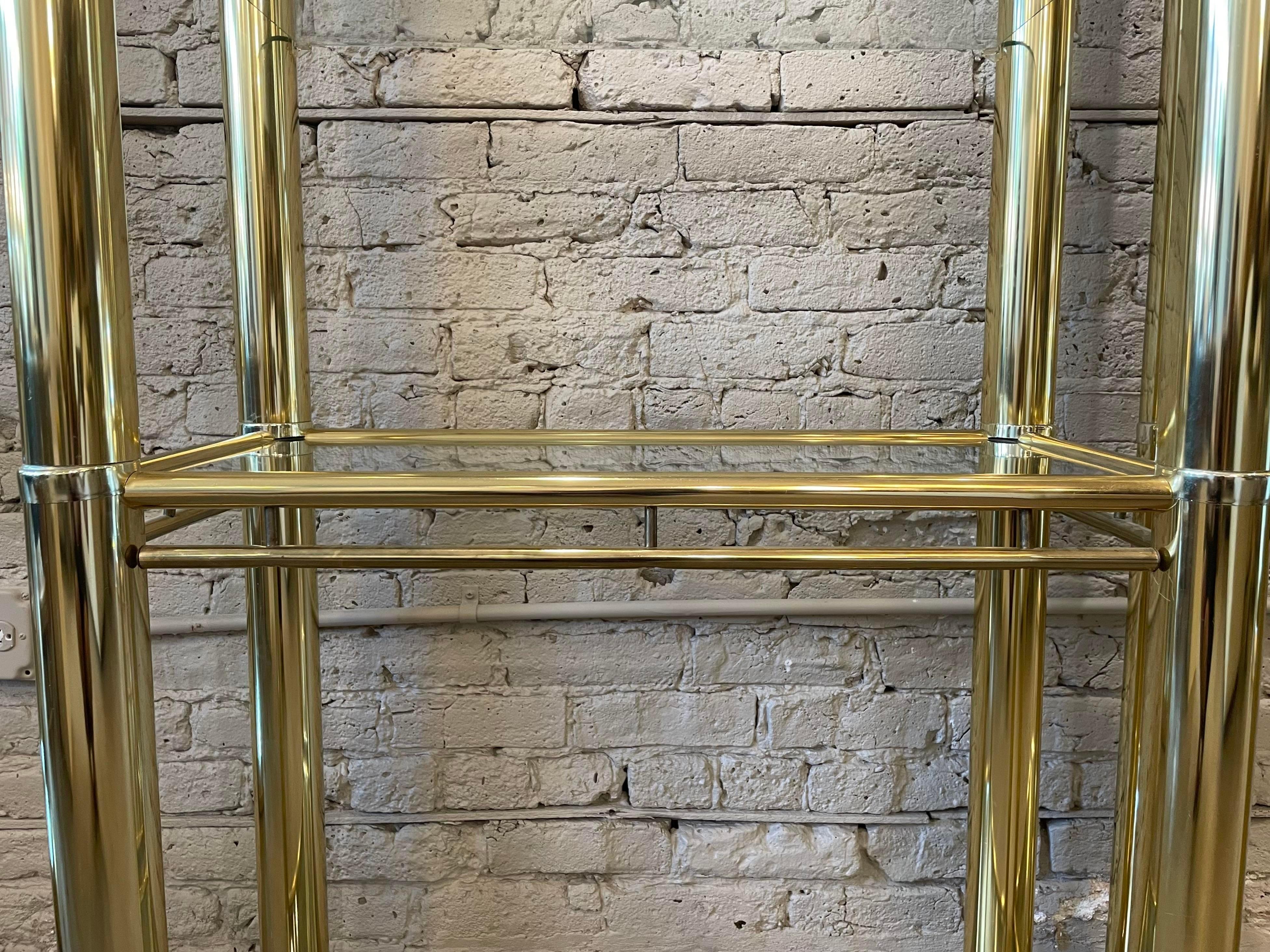Beautiful pair of brass Etageres in the style of Milo Baughman with 5 glass shelves. The brass and glass shelves are in very good condition.