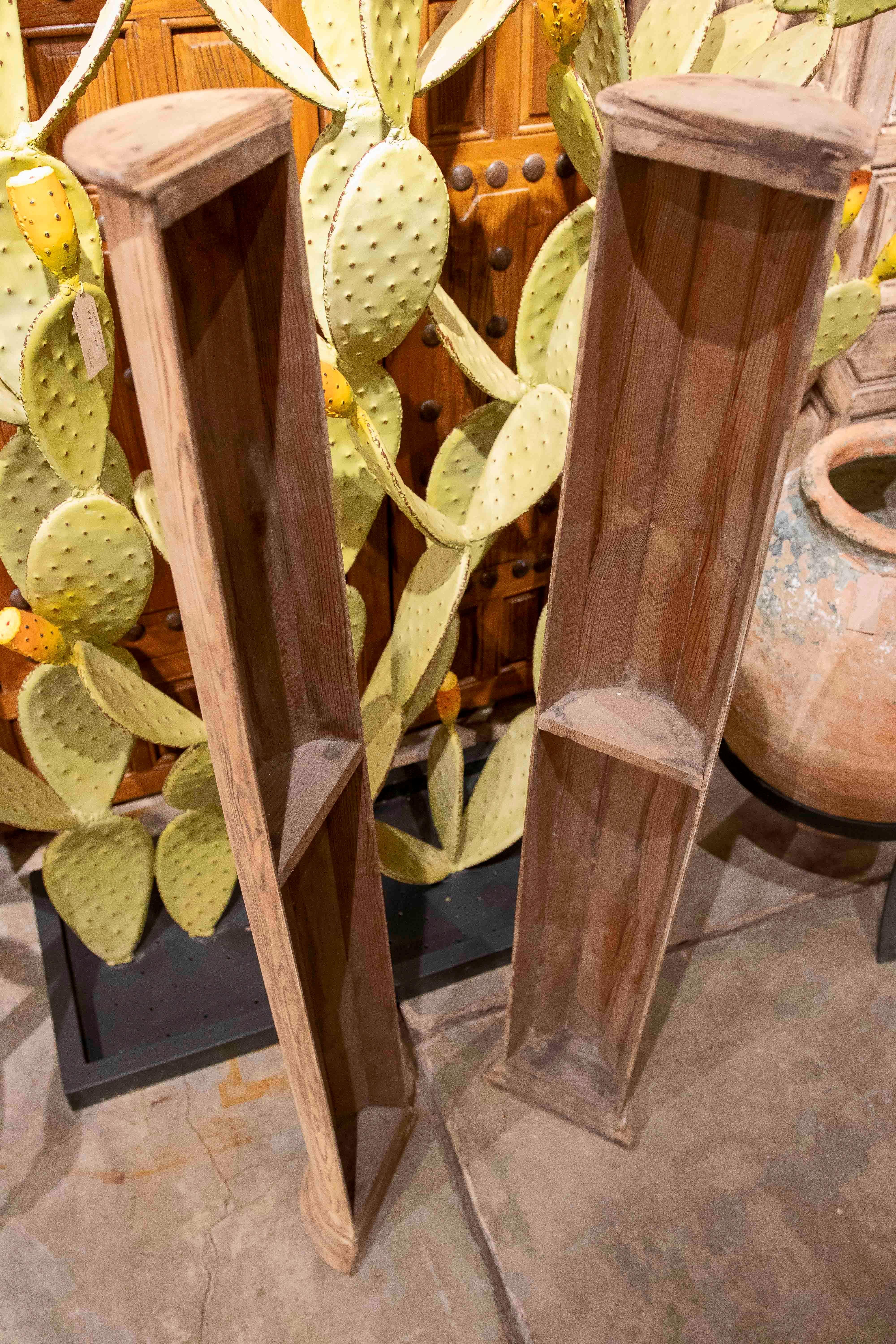 An elegant pair of decorative half-columns made of wood with a natural finish, ideal for adding an architectural and classic touch to any space. Their cylindrical design includes a molded base and a hollow structure with hidden compartments, making