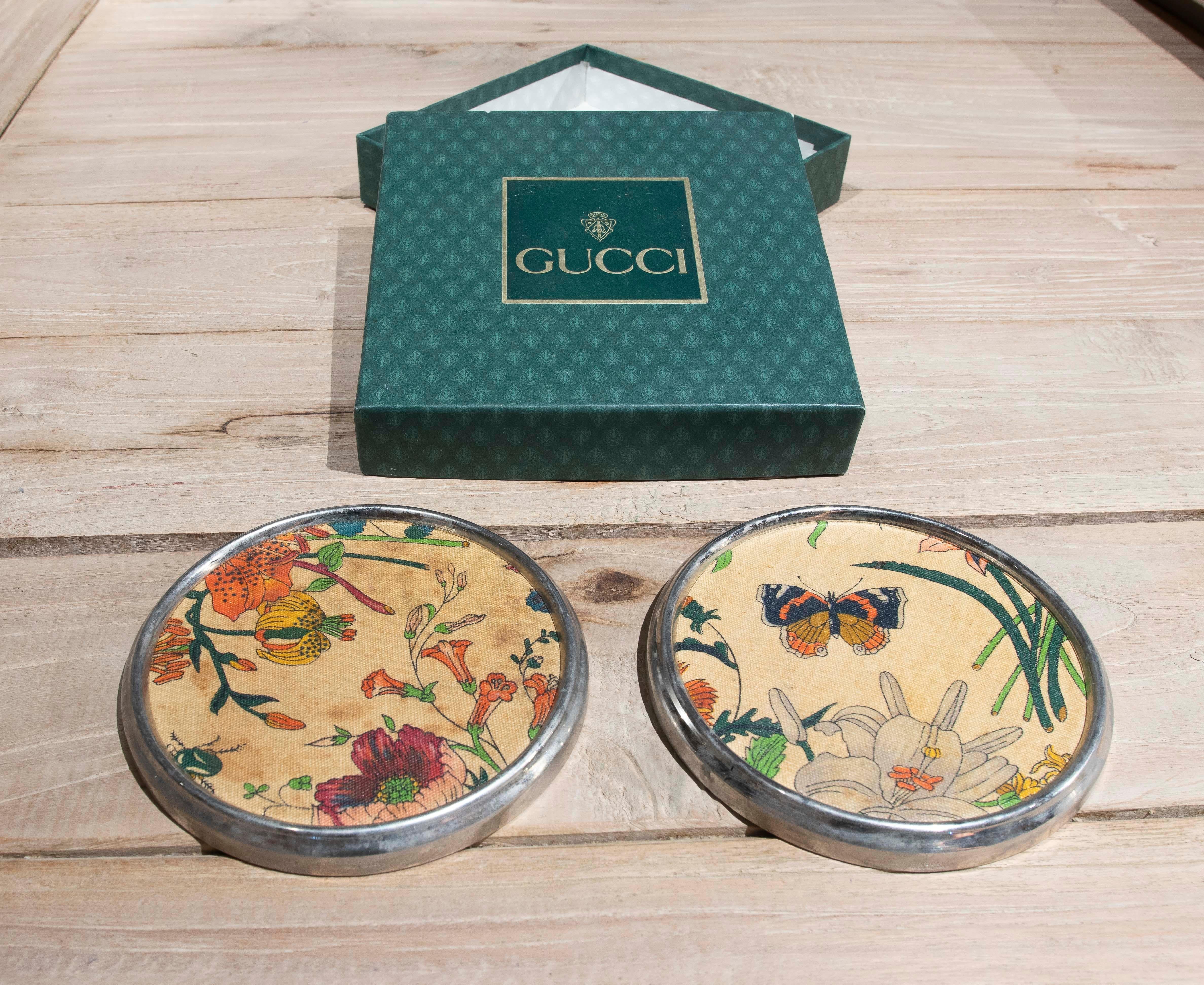 Par de posavasos Gucci de tela y borde plateado Años 80, Italia, con caja original. 
Tela con decoración de flores 
