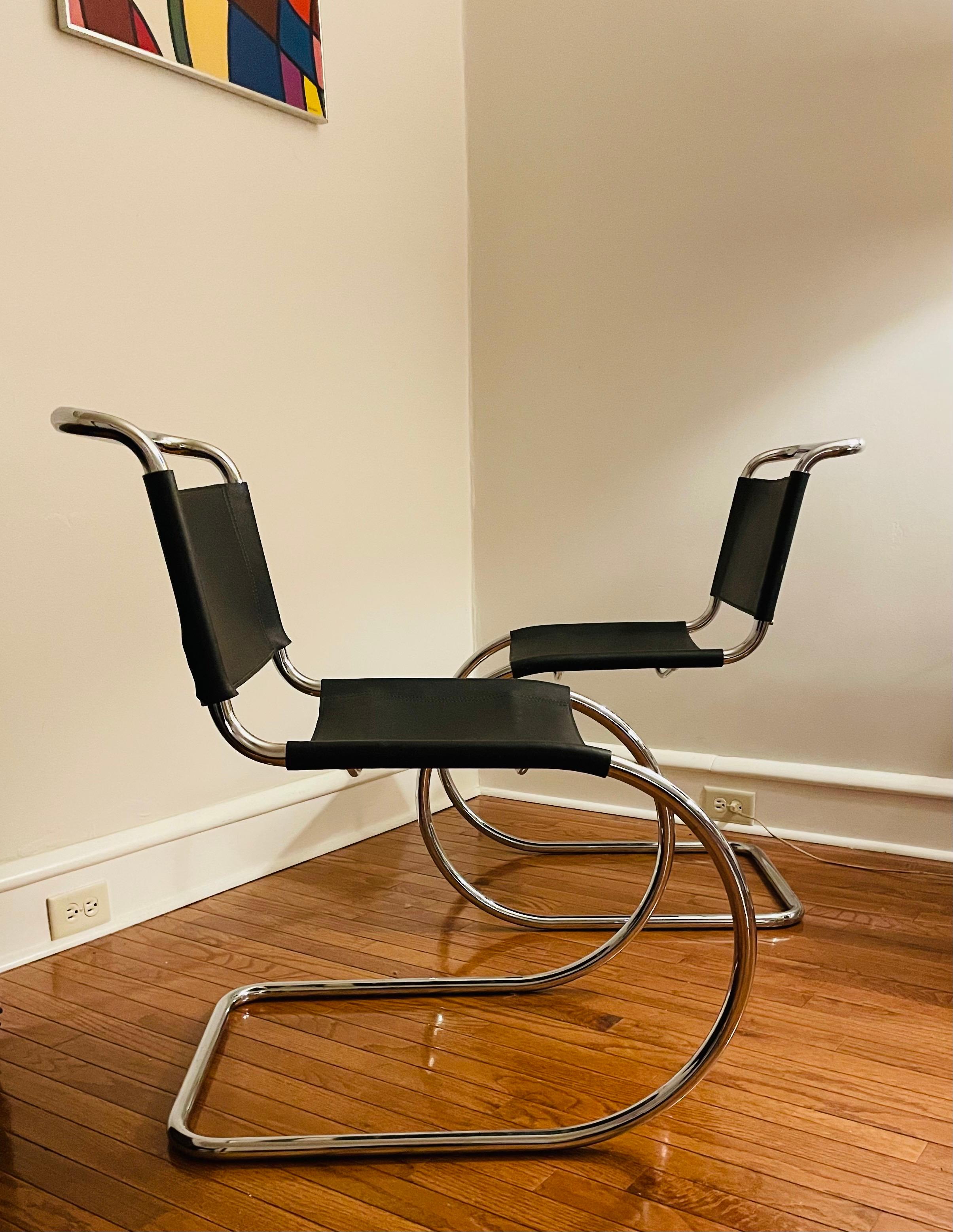 This is a pair of MR10 side dining chairs, initially designed by Ludwig Mies van der Rohe in 1927. These chairs date to the 1980s, and are unmarked. 

They have tubular steel cantilevered frames, and thick black calf leather seats and backs. They
