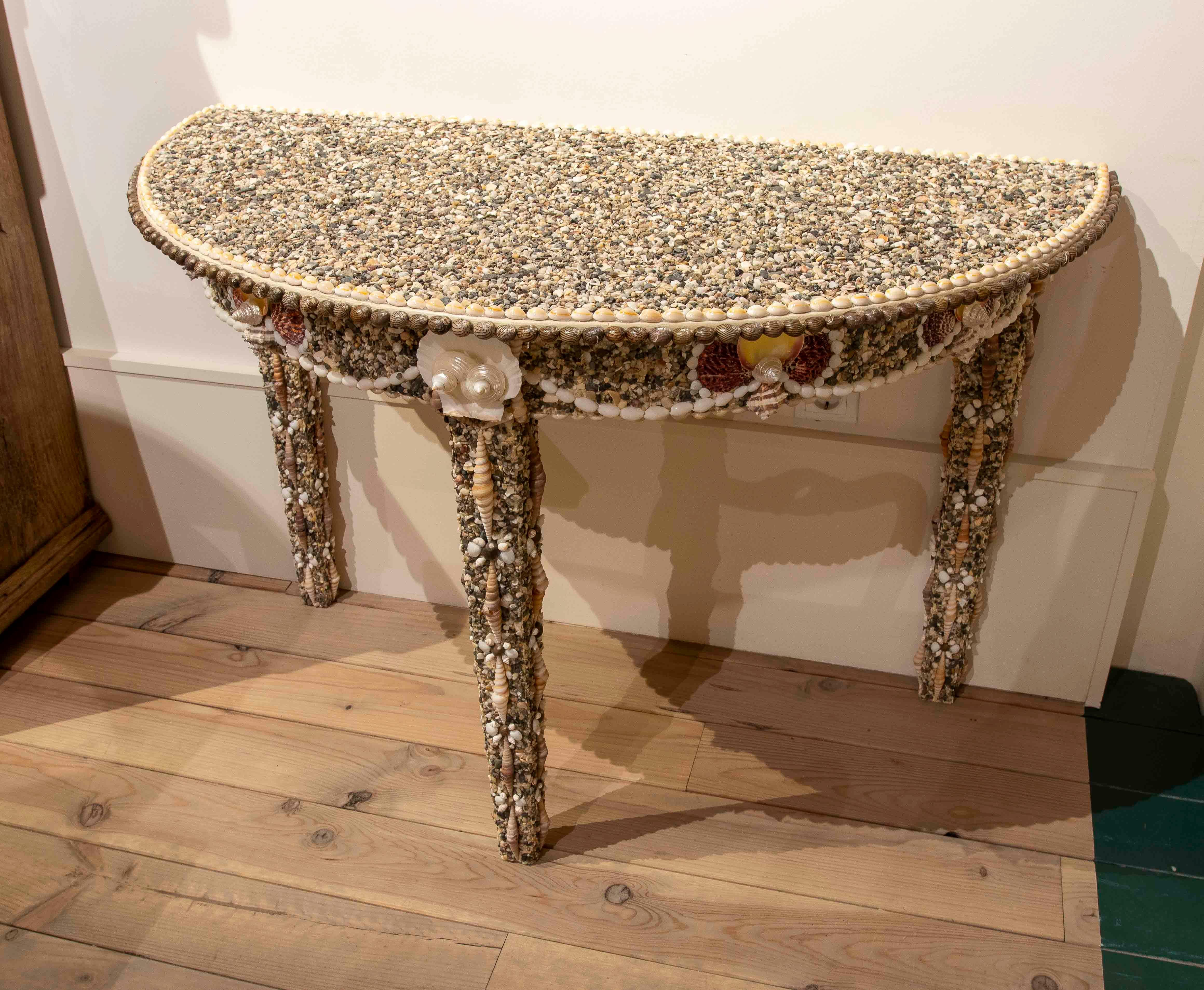 Set of two handcrafted semicircular console tables, completely covered with an exquisite selection of natural seashells. Each piece features a symmetrical and harmonious design, with unique decorative details that make them a perfectly complementary