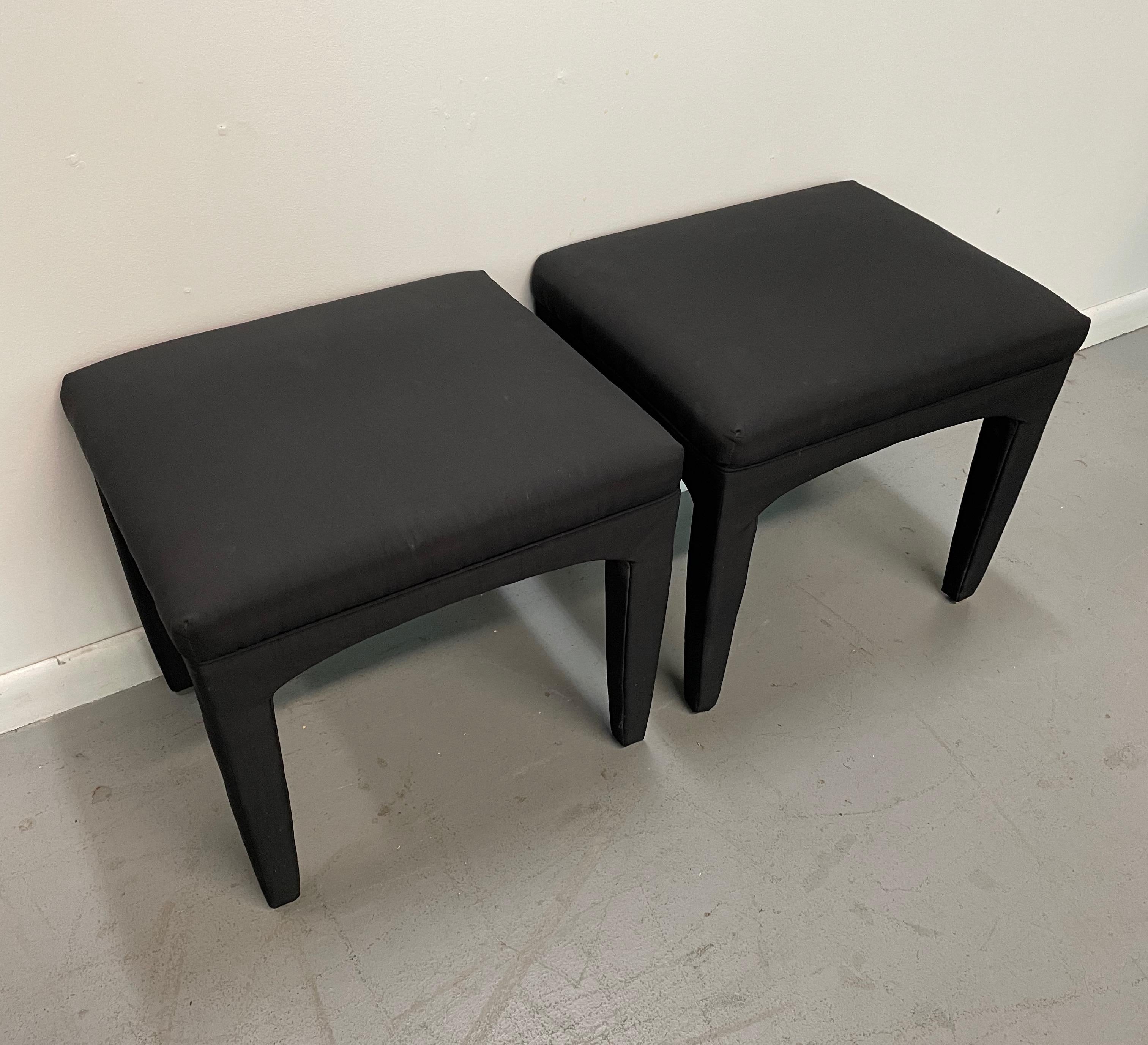 This pair of designer stools is upholstered in silky black fabric, they have a subtle arch to them that gives a graceful profile. These stools will ad style to any room.