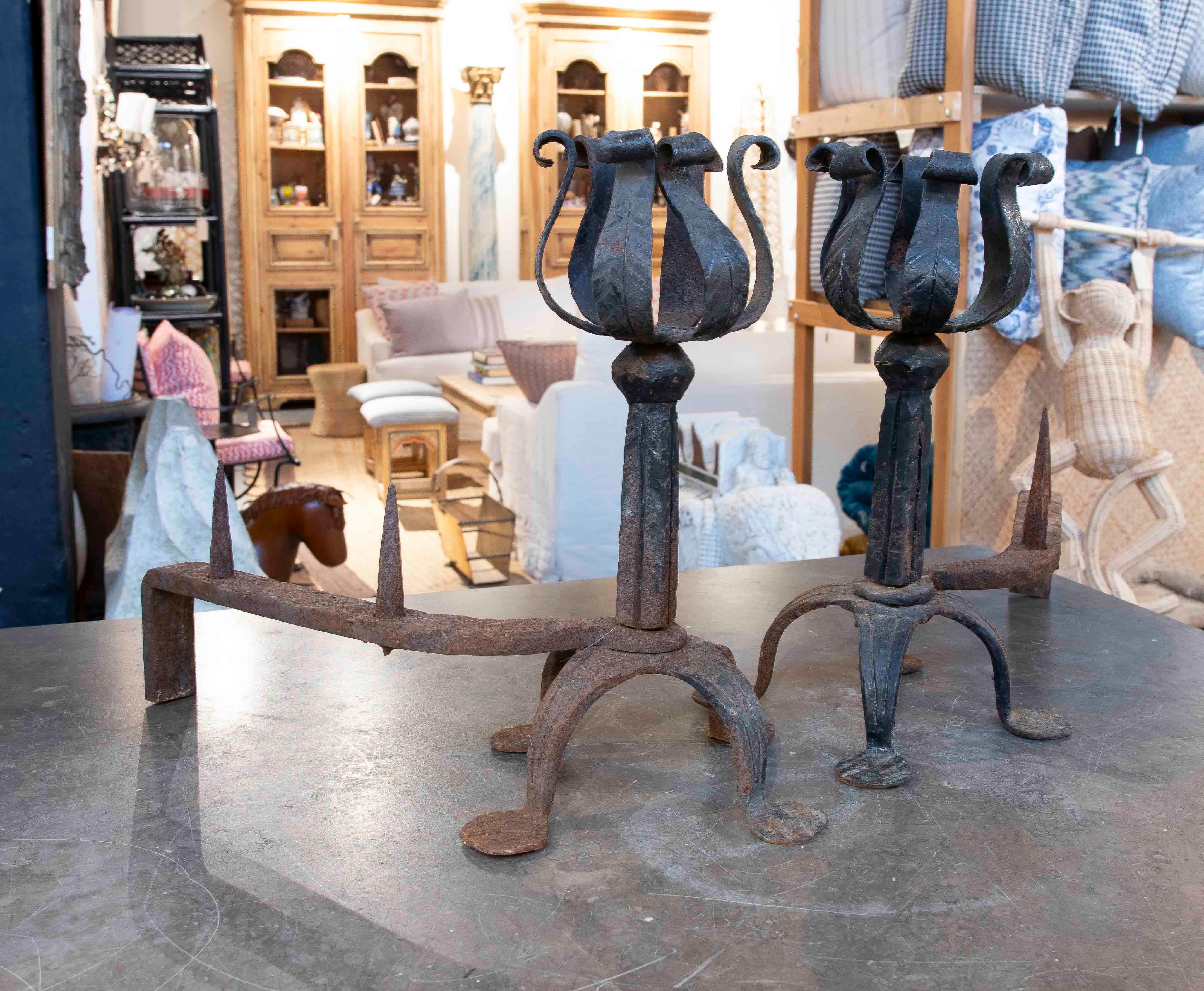 Imponente par de morillos de hierro forjado con un diseño rústico y robusto, ideales para complementar la estética de las chimeneas tradicionales. Estas piezas están hechas a mano, con detalles ornamentales en forma de tulipán que añaden carácter y