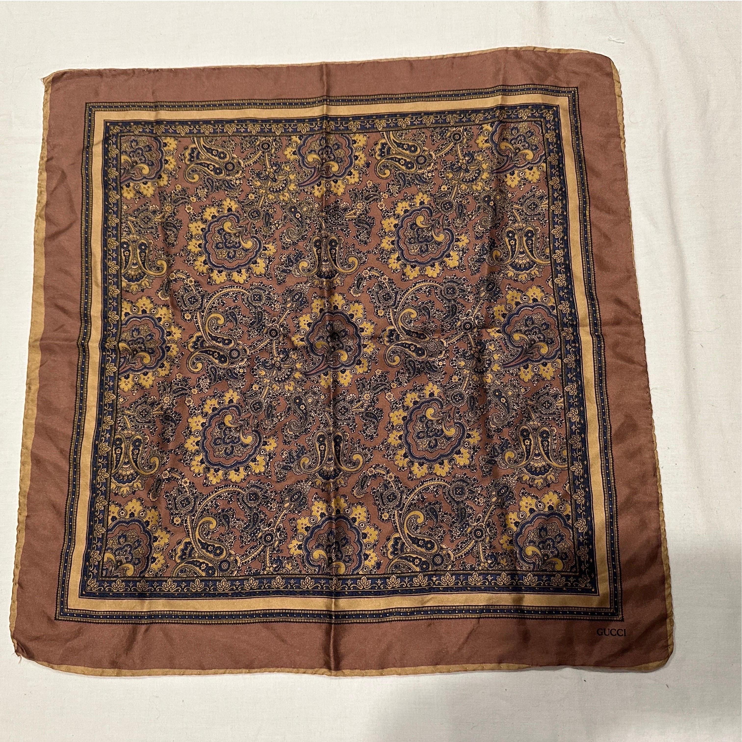 Este lujoso pañuelo cuadrado de generosas dimensiones está confeccionado en seda 100%, con un rico e intrincado estampado paisley, muy popular en aquella época.
La paleta de colores es sofisticada y atemporal, centrada en un borde y un fondo de seda