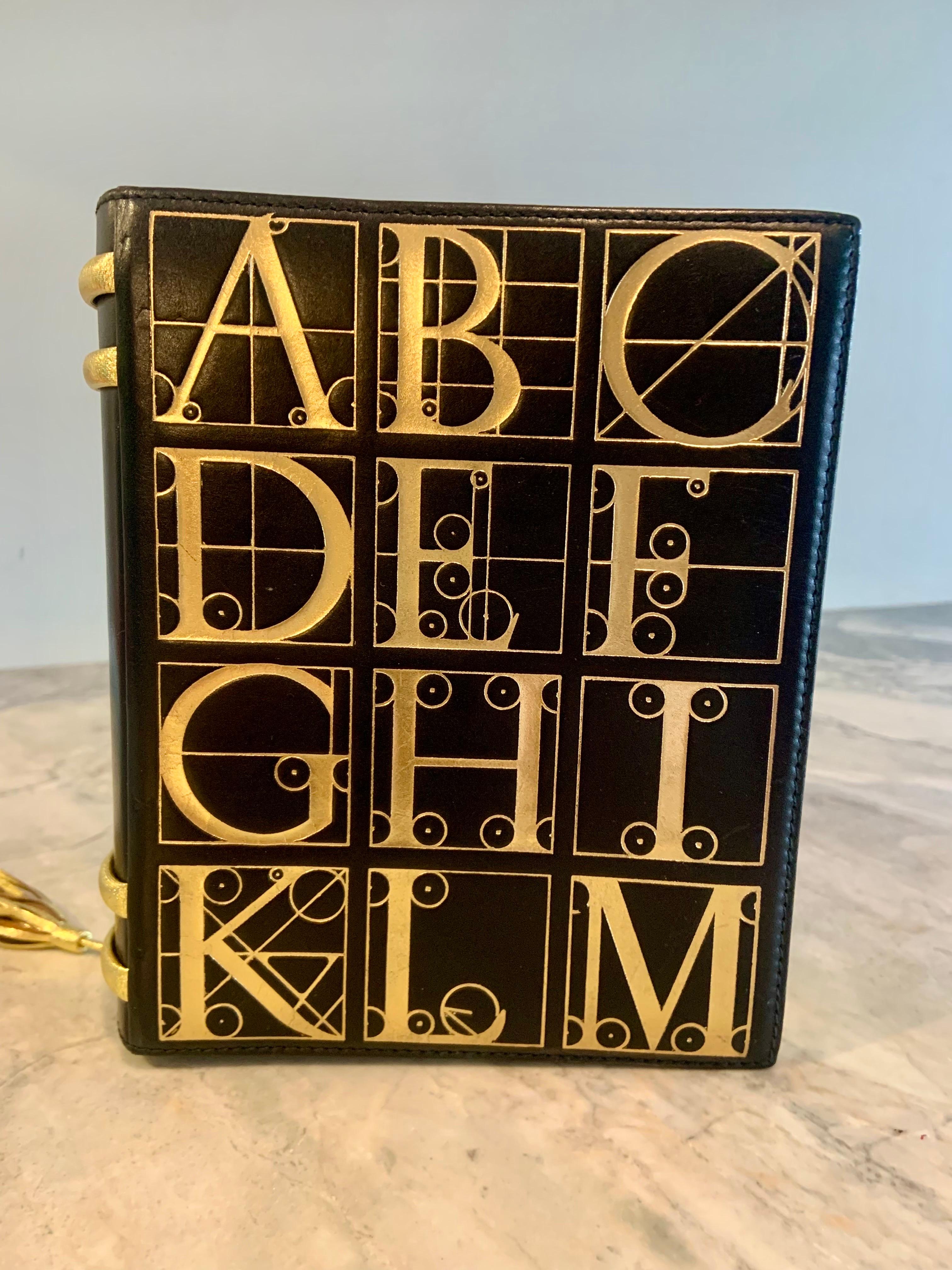 Paloma Picasso designed a group of book shaped handbags in the 1980's. This one has the alphabet on the front and back in gold on black leather. There is a gold leather tassel bookmark, the spine of the book bag has gold leather bands matching the