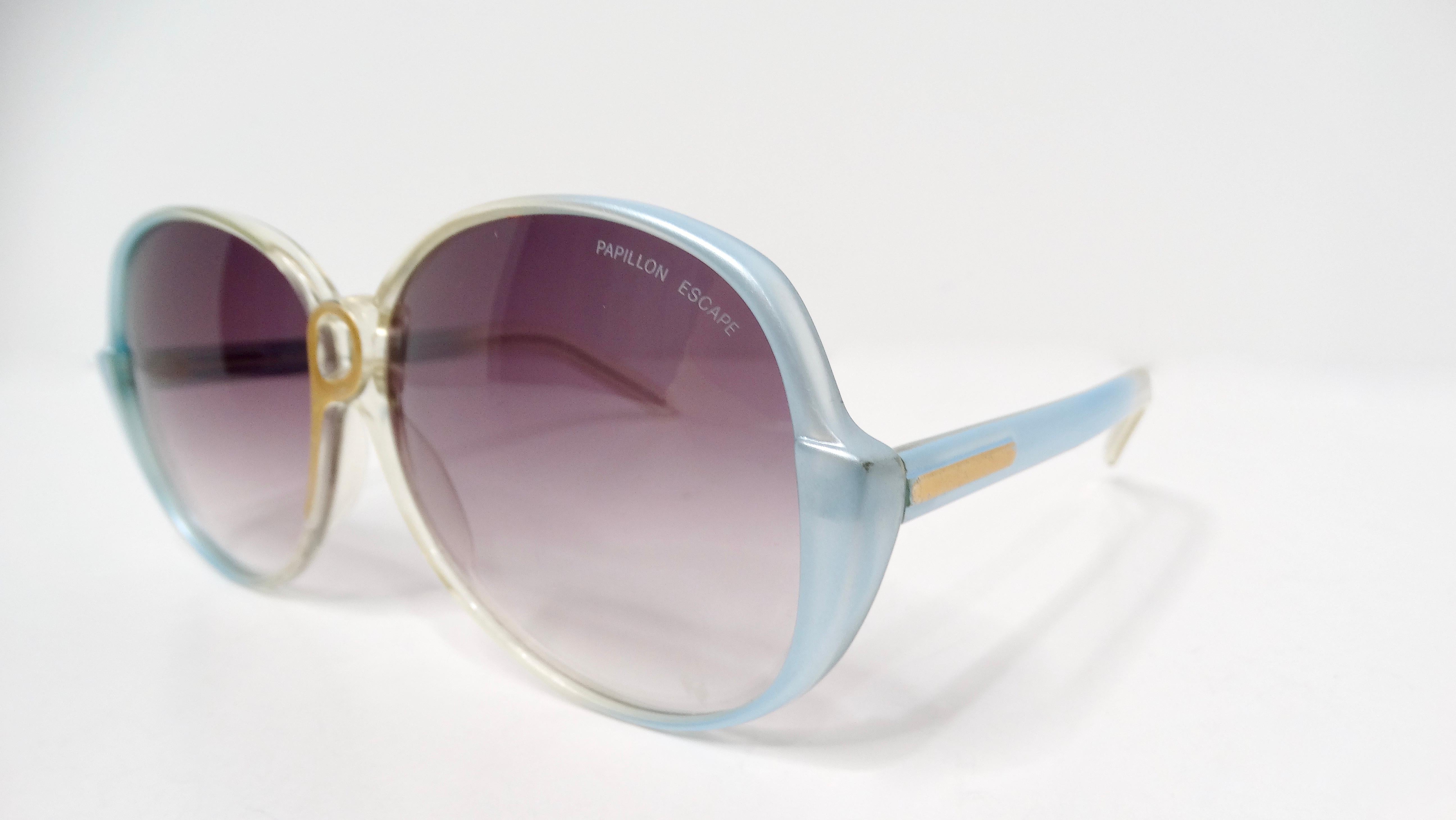 Entrez dans le chic rétro avec ces lunettes de soleil Papillon des années 1980, une pièce audacieuse qui capture l'essence de l'époque. Les lentilles rondes surdimensionnées, teintées en bleu clair avec un subtil dégradé de violet, évoquent une