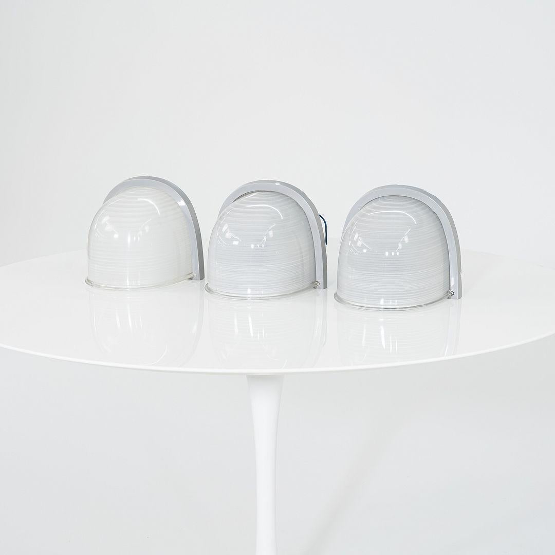 Se trata de un aplique Paride 20, diseñado por Angelo Mangiarotti para Artemide en 1980. El precio indicado incluye un candelabro, y tenemos tres disponibles para comprar. 
 
 Sus pantallas están formadas por un grueso cristal transparente, redondo