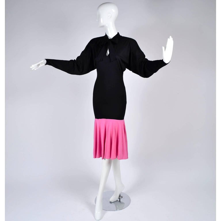 This 1980's vintage Patrick Kelly dress can easily be worn and be on trend today! The dress is in a black jersey with a gorgeous pink color block hem. The dress has a perfectly fitted body, dolman sleeves and a keyhole tie at the neck. We have this