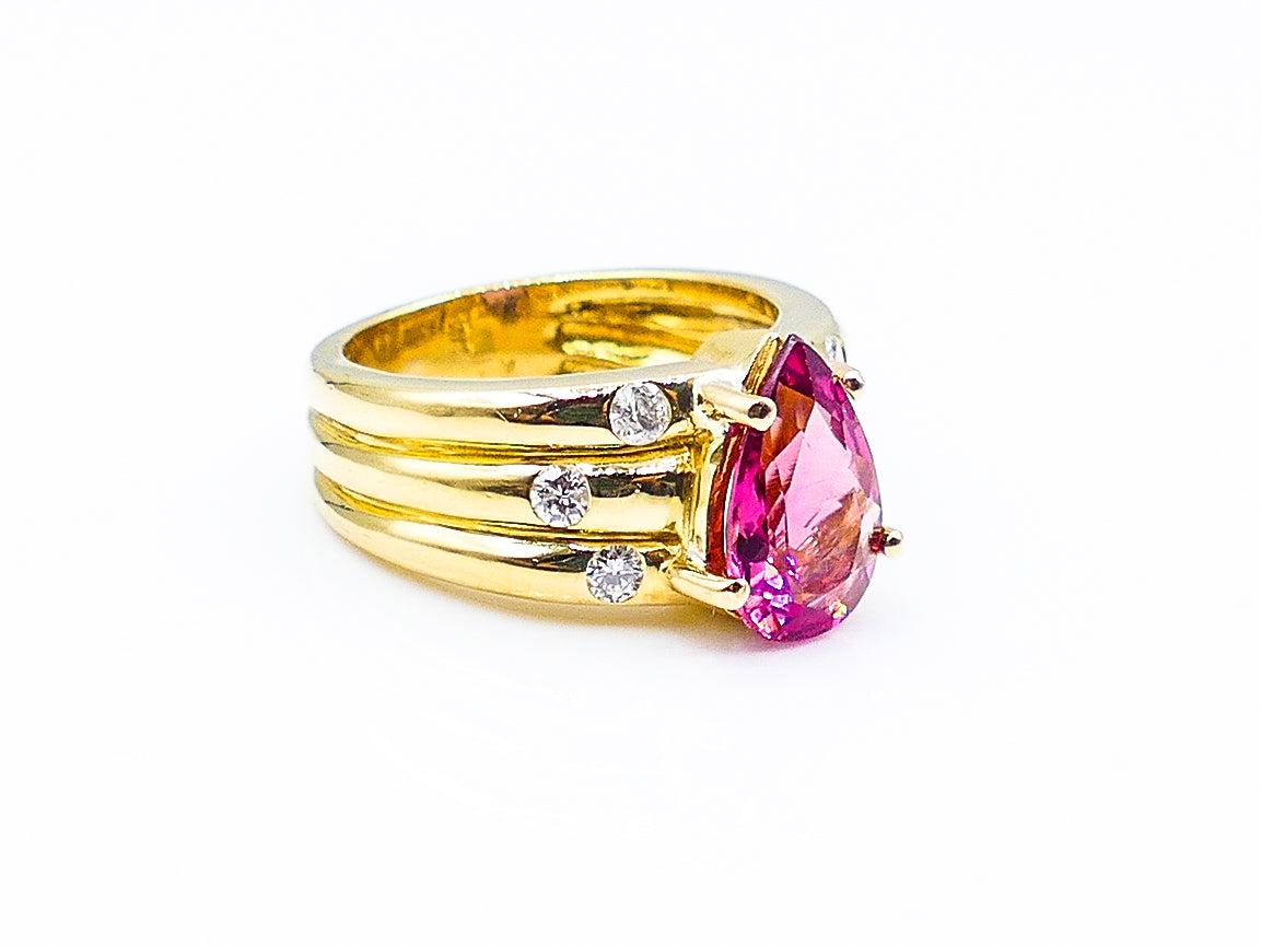 This bold pear shaped Pink Tourmaline is flanked by 3 small round cut diamonds on either side totaling about .33 carats. The layered look of the 18 Karat gold band adds a unique dimension to the piece.

Size 7

10 g