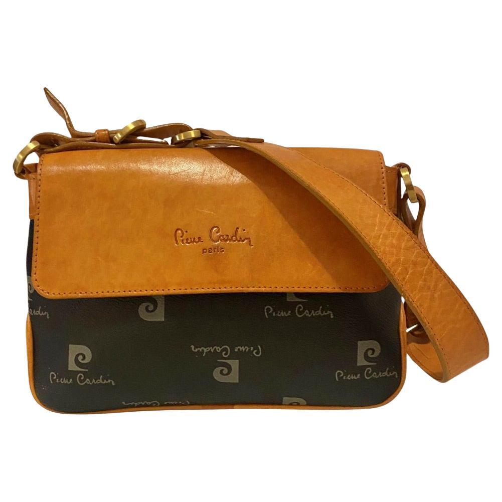 1980s Pierre Cardin Black Tan Logo Flap Shoulder Bag, black leather exterior,  zippered closure, tan leather flap, gold matte hardware, zipped interior pocket, adjustable leather strap

Condition: 1980s, good, some light sign of w, ear as expected,