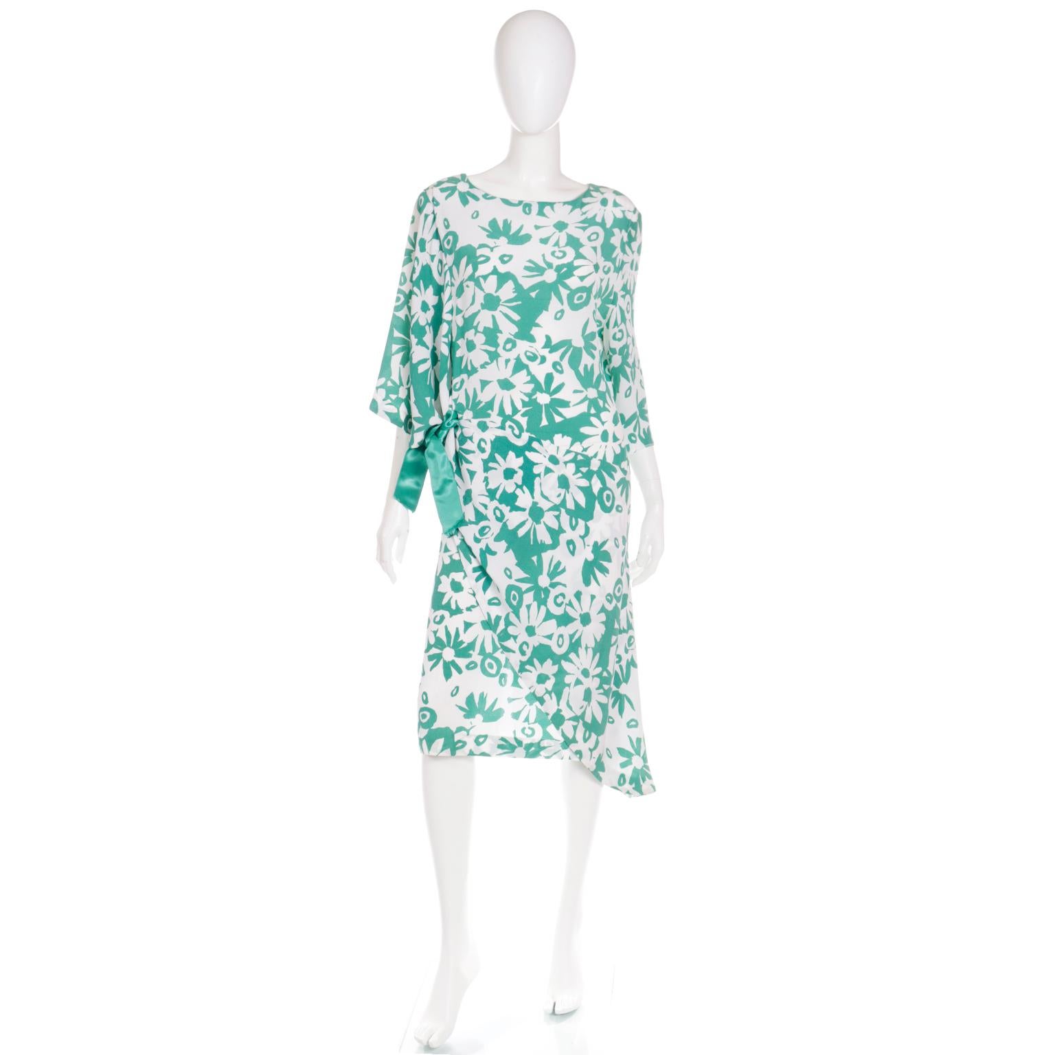 This pretty Creation Pierre Cardin Paris vintage dress is in a bold green and white floral print and it has incredible style details. This 1920's inspired day or evening dress has an asymmetrical silhouette with a tie at the side featuring a green