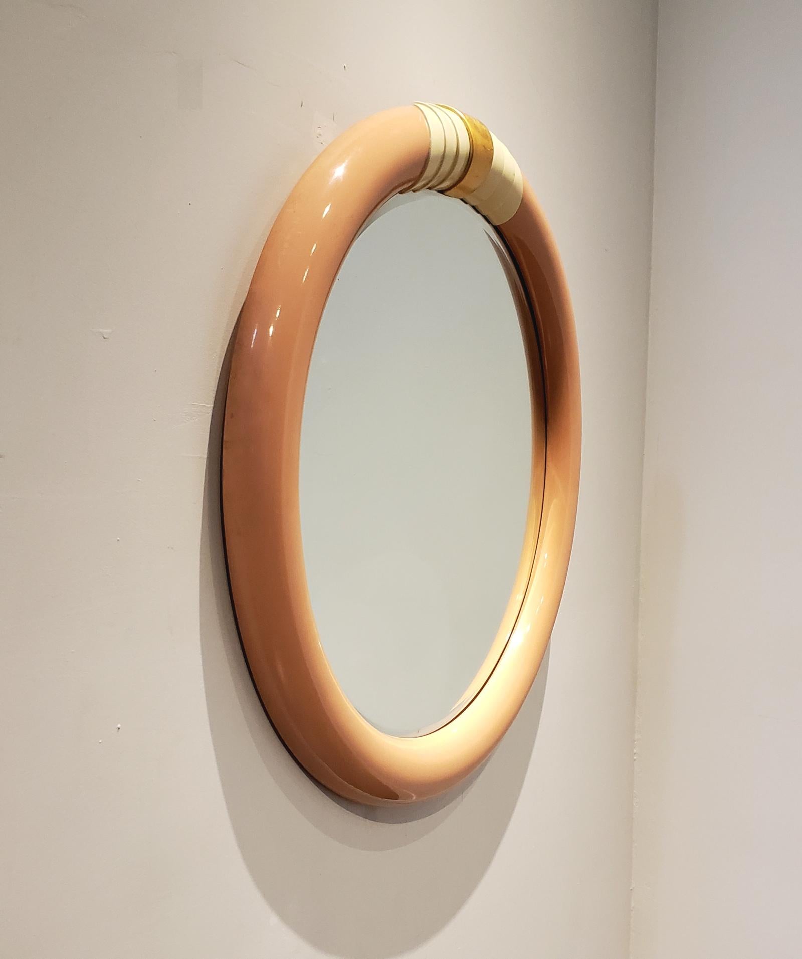 1980s pink circular wall mirror with white and gold decorative accents on top. Lovely, glossy blush pink color. Heavy, quality construction.