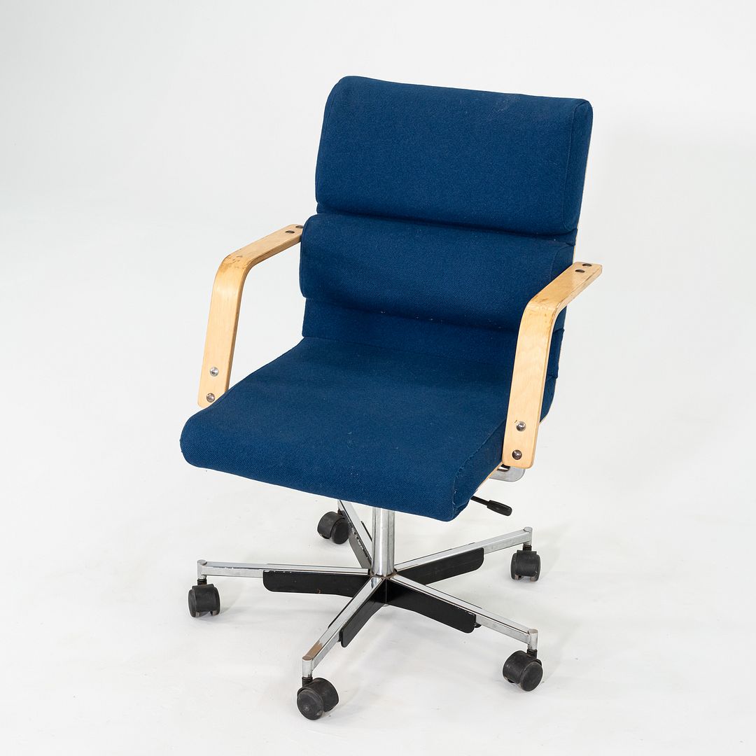 This is a Plaano Chair, originally designed by Yrjo Kukkapuro in 1974. This particular example was produced by Avarte in Finland circa the 1980s. The chair is comprised of a steel 5-star base, a seat upholstered in blue fabric, and birch armrests. 
