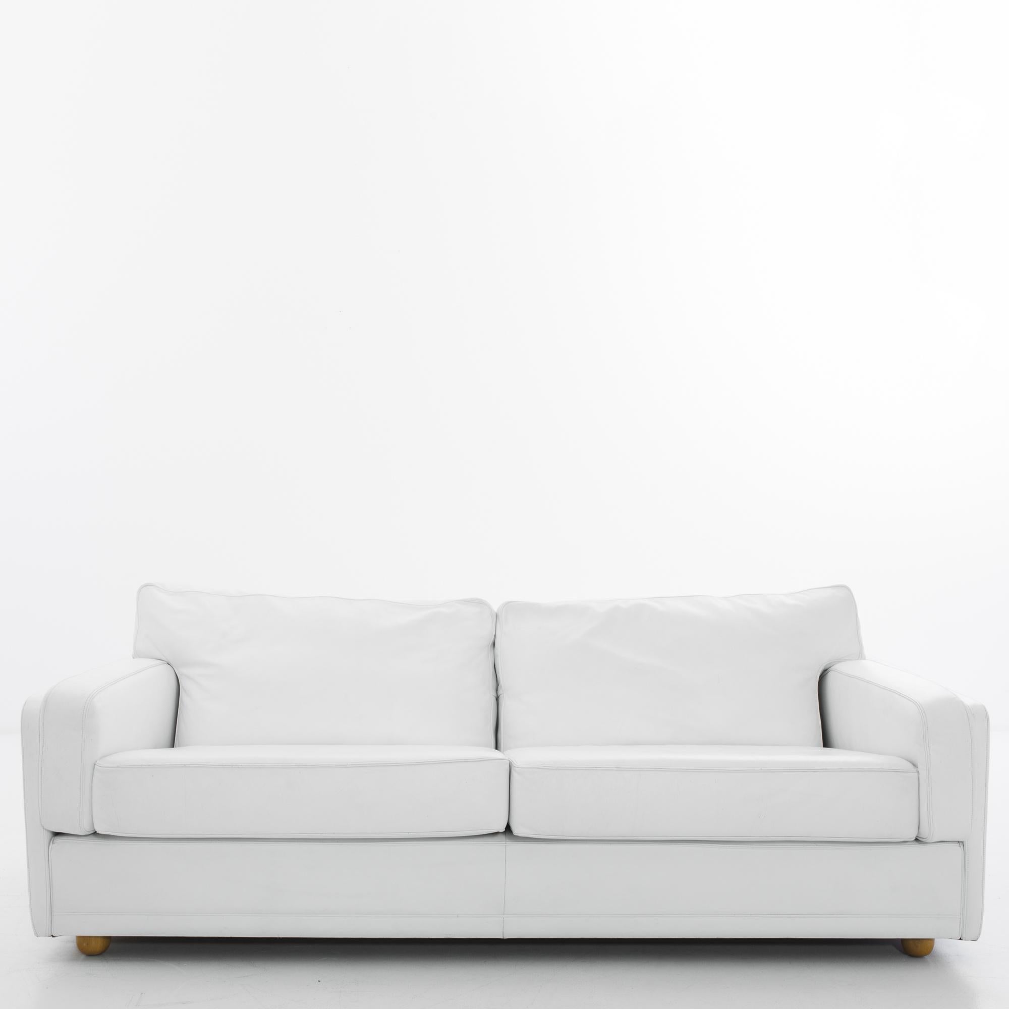A 1980s white leather sofa from Italian furniture makers Poltrona Frau. The brilliant white of the leather brings a crisp polish to the deep-seated silhouette. Ample sofa cushions are set at a leisurely recline; wooden feet provide subtle elevation.