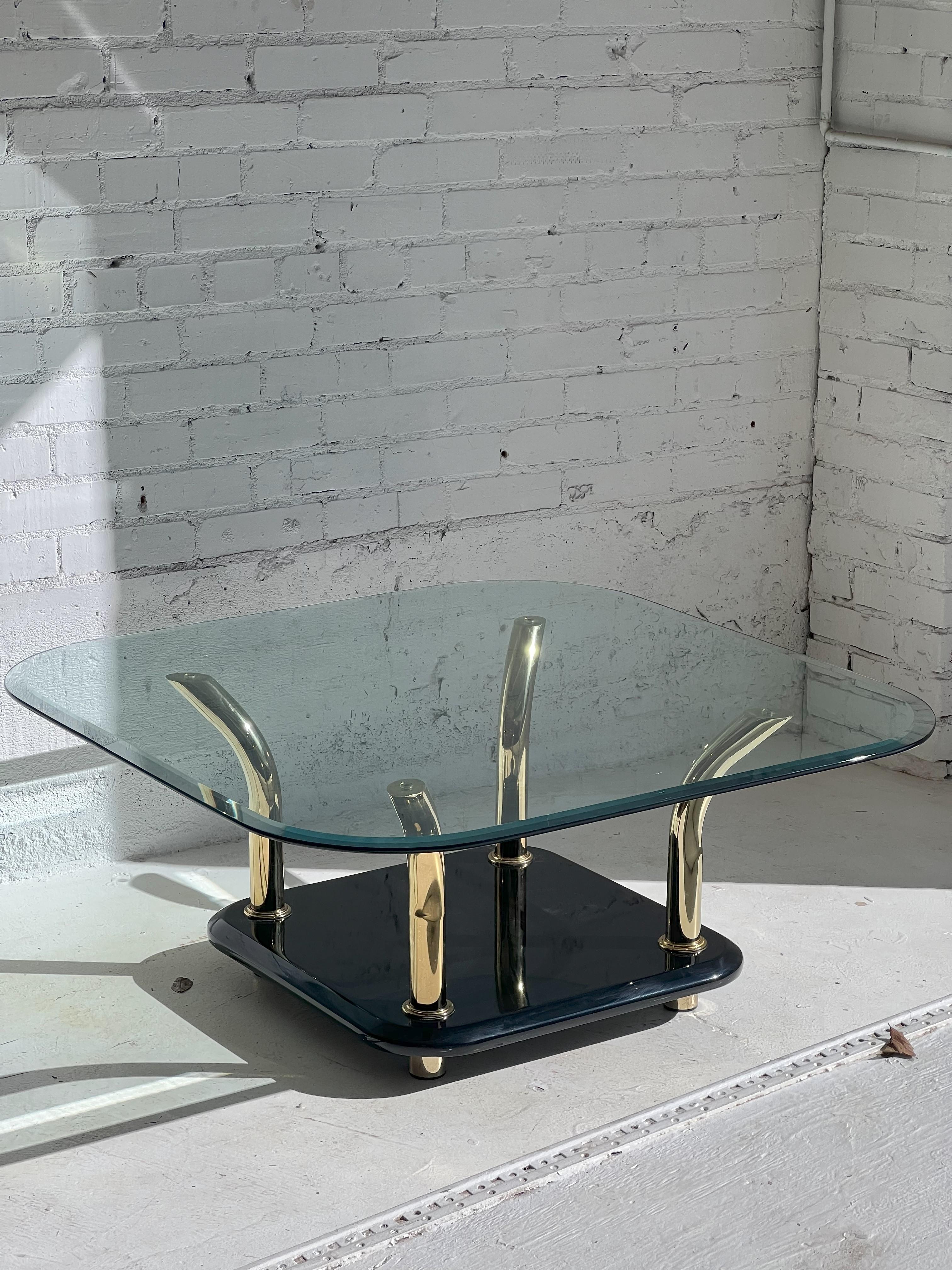 This elegant post modern meets Miami Regency 1980's coffee / cocktail table is attributed to Karl Springer and would look great in a Modern or Mid-Century decor. It features sculptural brass finished horns with a beautiful glossy black base. The