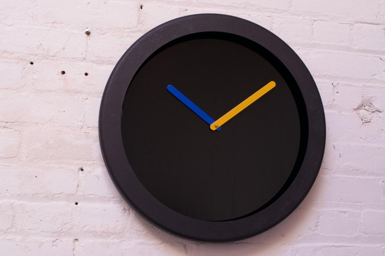 1980s wall clock by Empire Art Products of Glendale, NY. Chic, minimal, Postmodern style with a black glass surface contrasted with blue and yellow hands. Original condition with only minimal wear to the yellow hand (two flecks, as shown).
Battery