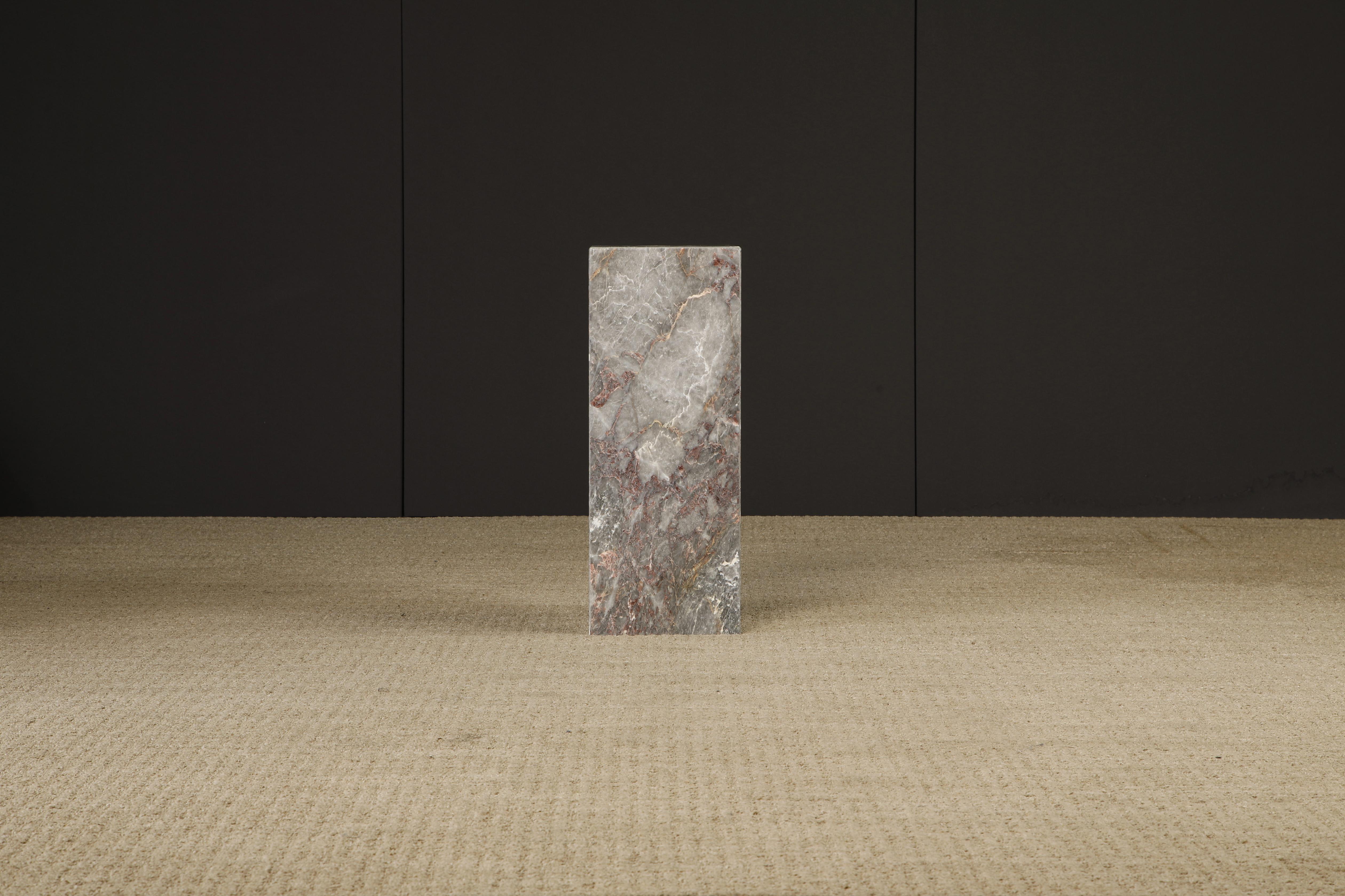 This beautiful 1980s Post-Modern exotic marble column pedestal features exotic graining and coloration with hues of grey, pink, red and gold. 

We have a matching pedestal that is slightly taller at 29.5