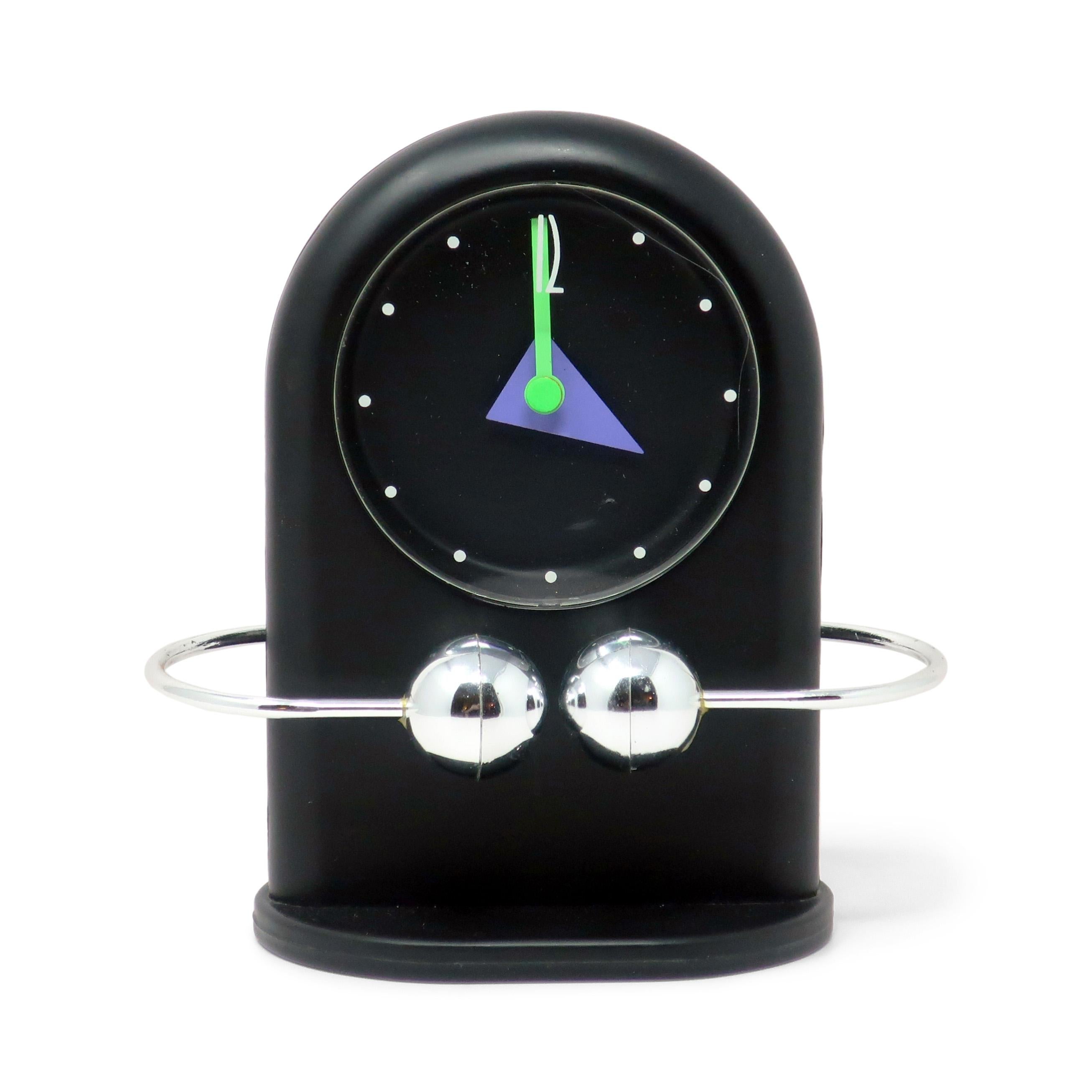 A fantastic postmodern vintage desk, mantel, or shelf clock with a oval base, rounded top case, geometric hands, and a silver pendulum 'ring' above the base of the clock that keeps the beat to the second by oscillating from left to right in