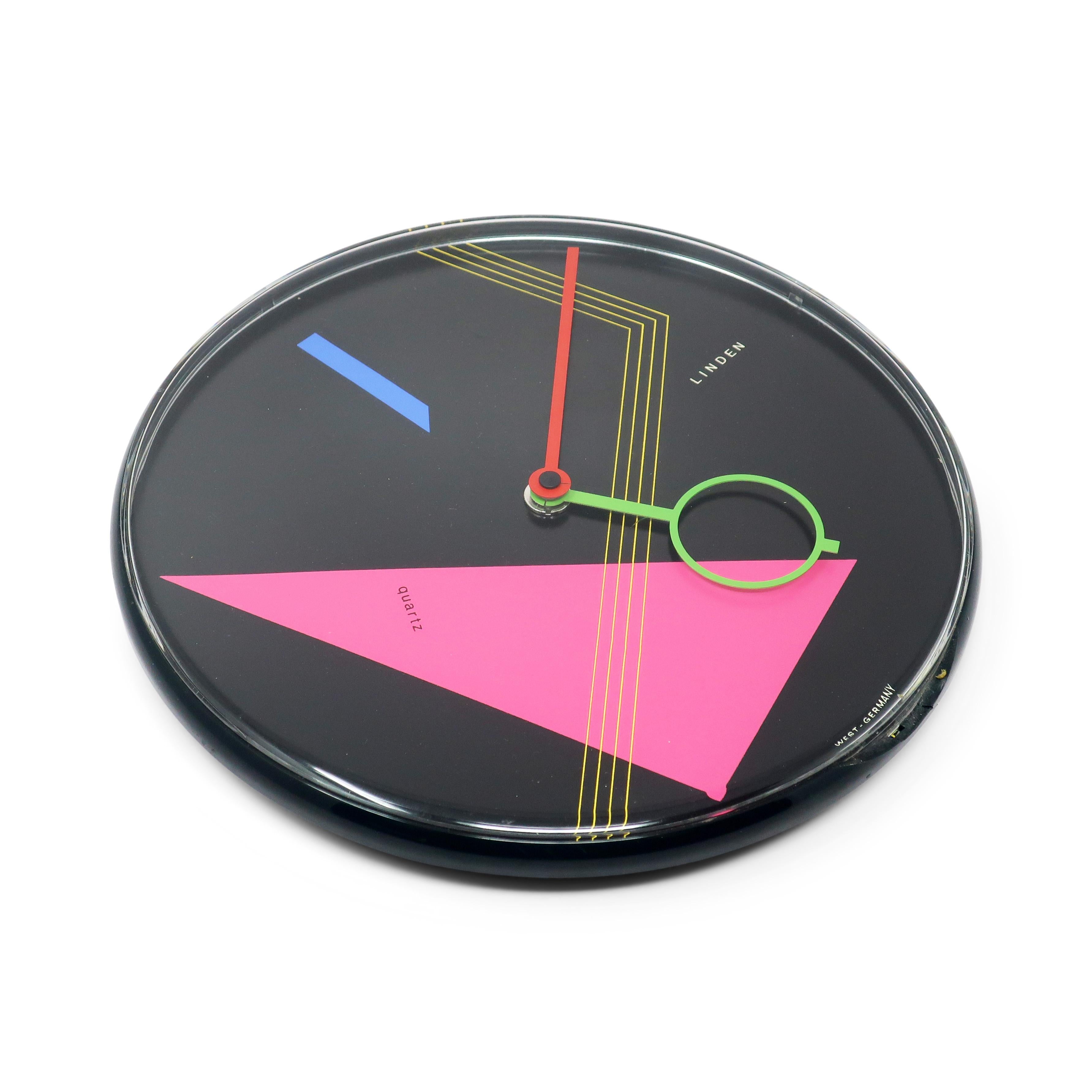 A beautiful postmodern wall clock from the 1980s by West German clockmaker Linden.  It has a black case, black face with geometric accents, and red and green hands,  Striking contrast and fantastic pop of colors with pink, blue, and yellow