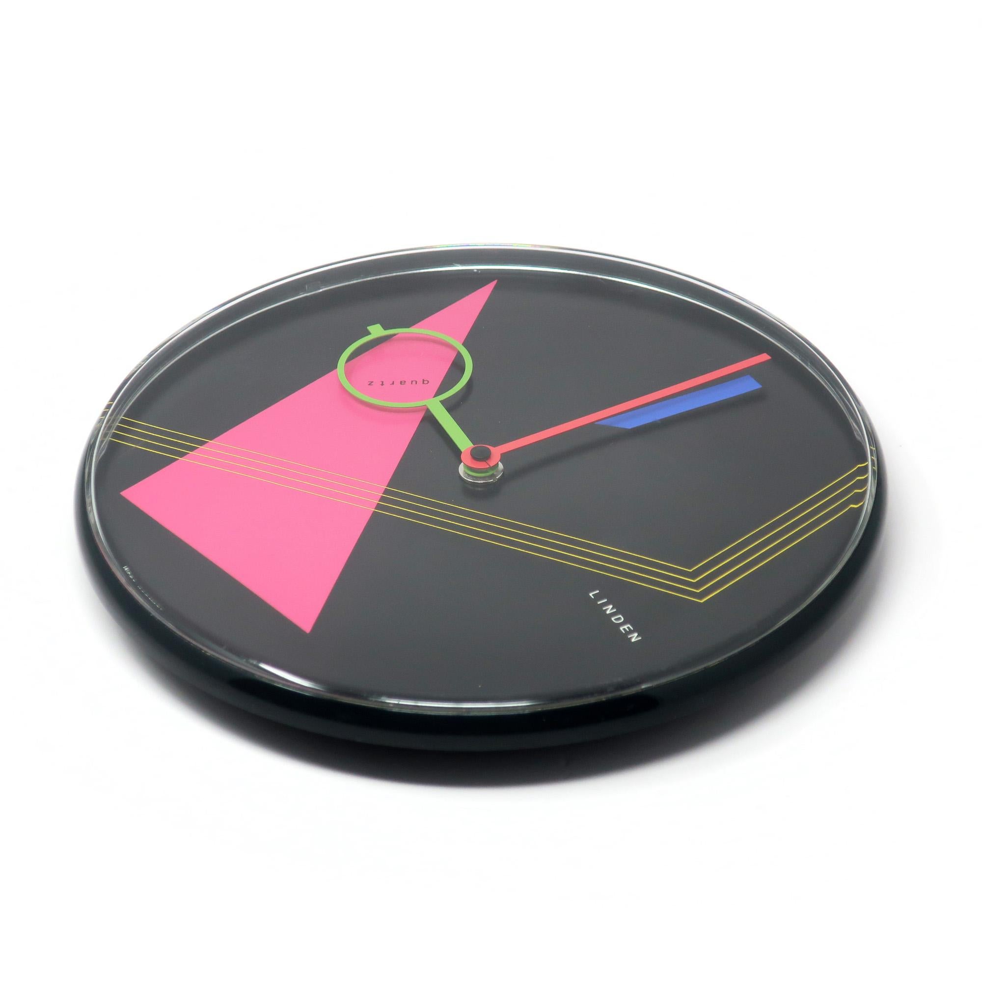 A beautiful postmodern wall clock from the 1980s by West German clockmaker Linden.  It has a black case, black face with geometric accents, and red and green hands,  Striking contrast and fantastic pop of colors with pink, blue, and yellow