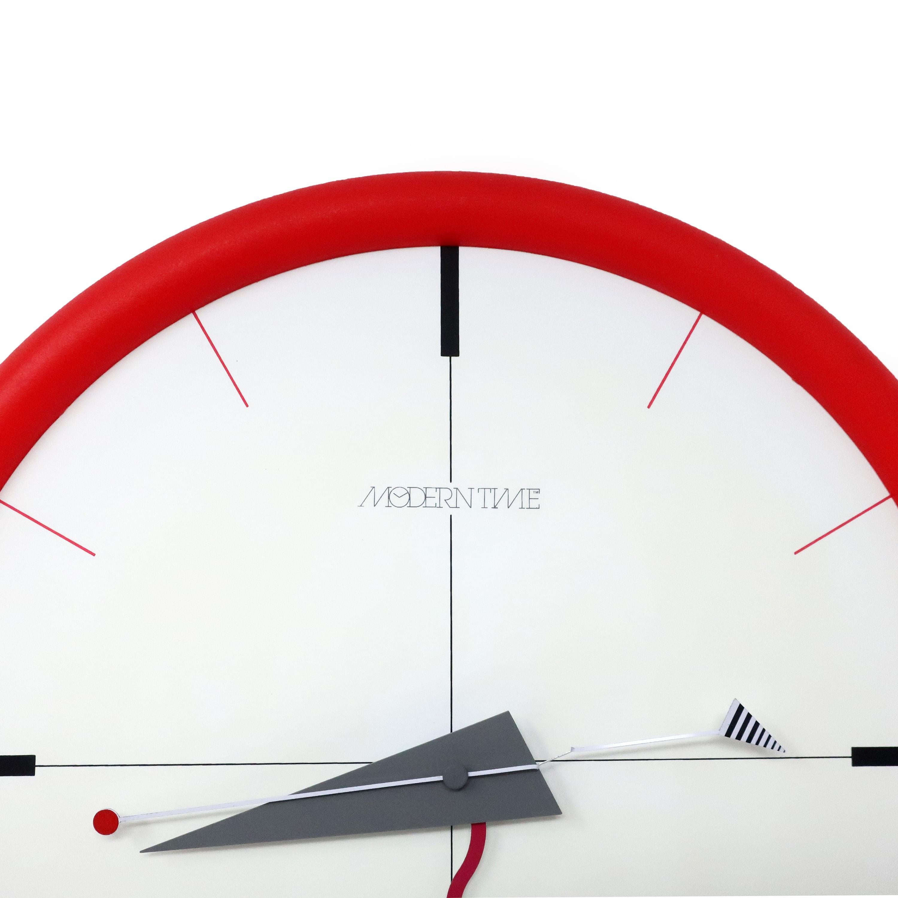 A stunning postmodern wall clock with multi-color accents from Canetti's Moderntime Collection. Red plastic frame, white face, and red, black, and gray accents. It perfectly walks a line between understated & sophisticated and bright &