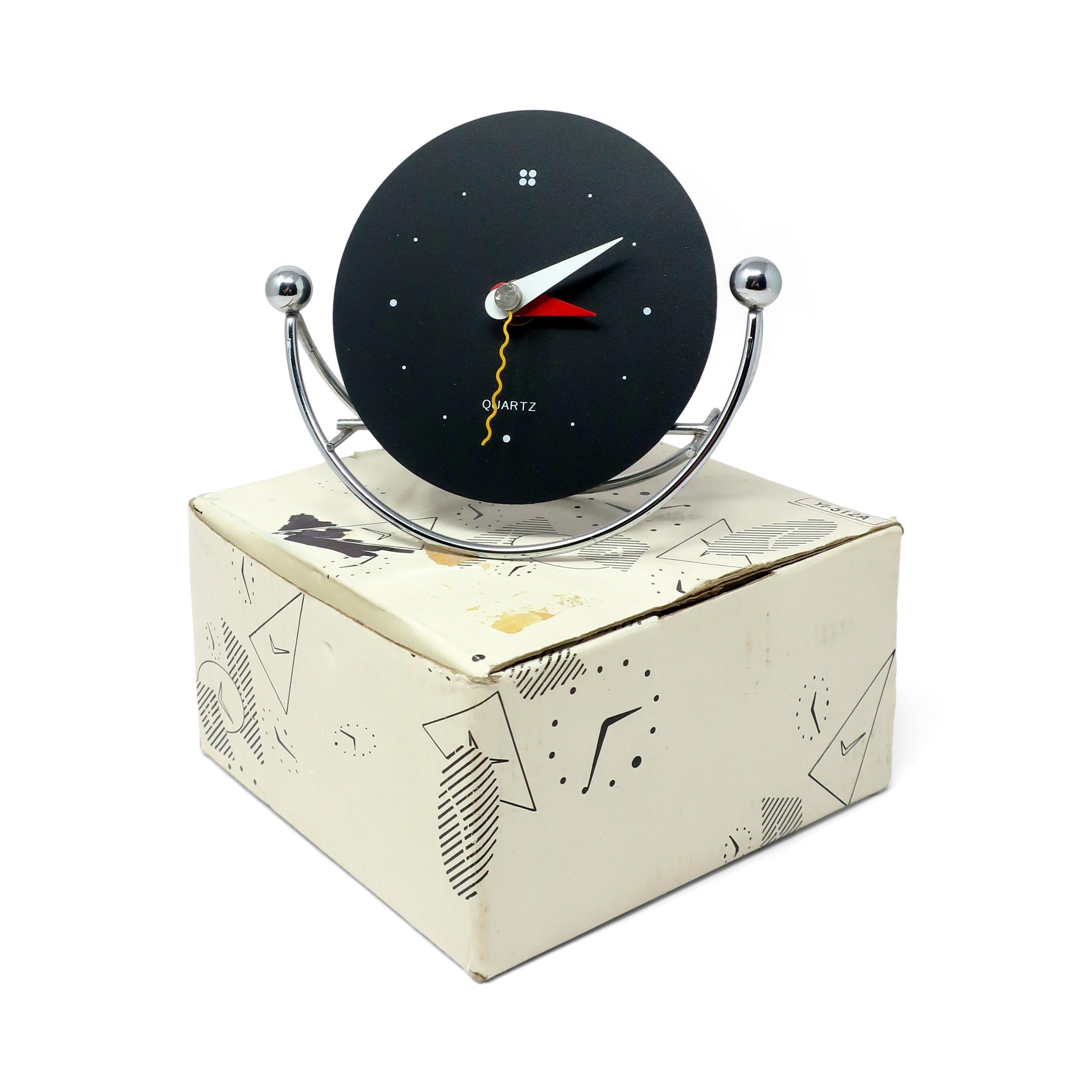 A fantastic postmodern vintage desk, mantel, or shelf clock in the style of Shohei Mihara’s designs for Wakita.   With a black face, red, white and yellow hands, and chrome rocking base, it has the perfect postmodern look. 

In very vintage
