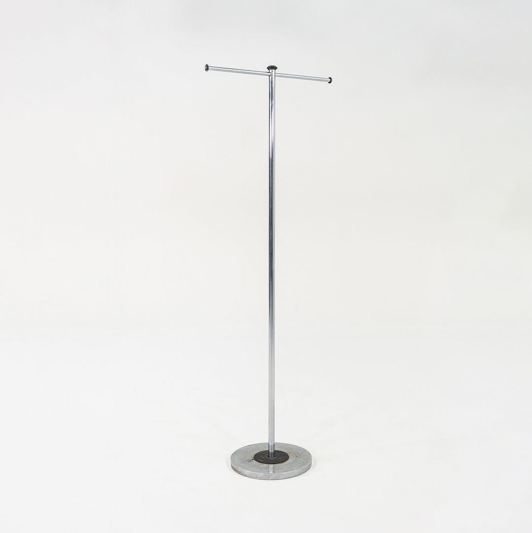 Questo è un appendiabiti moderno, progettato e prodotto negli anni '80. Ha un gambo in acciaio cromato e accenti in nero opaco. Ha la forma di una T e una base rotonda che ne garantisce la stabilità. Il design ricorda molti pezzi italiani degli anni