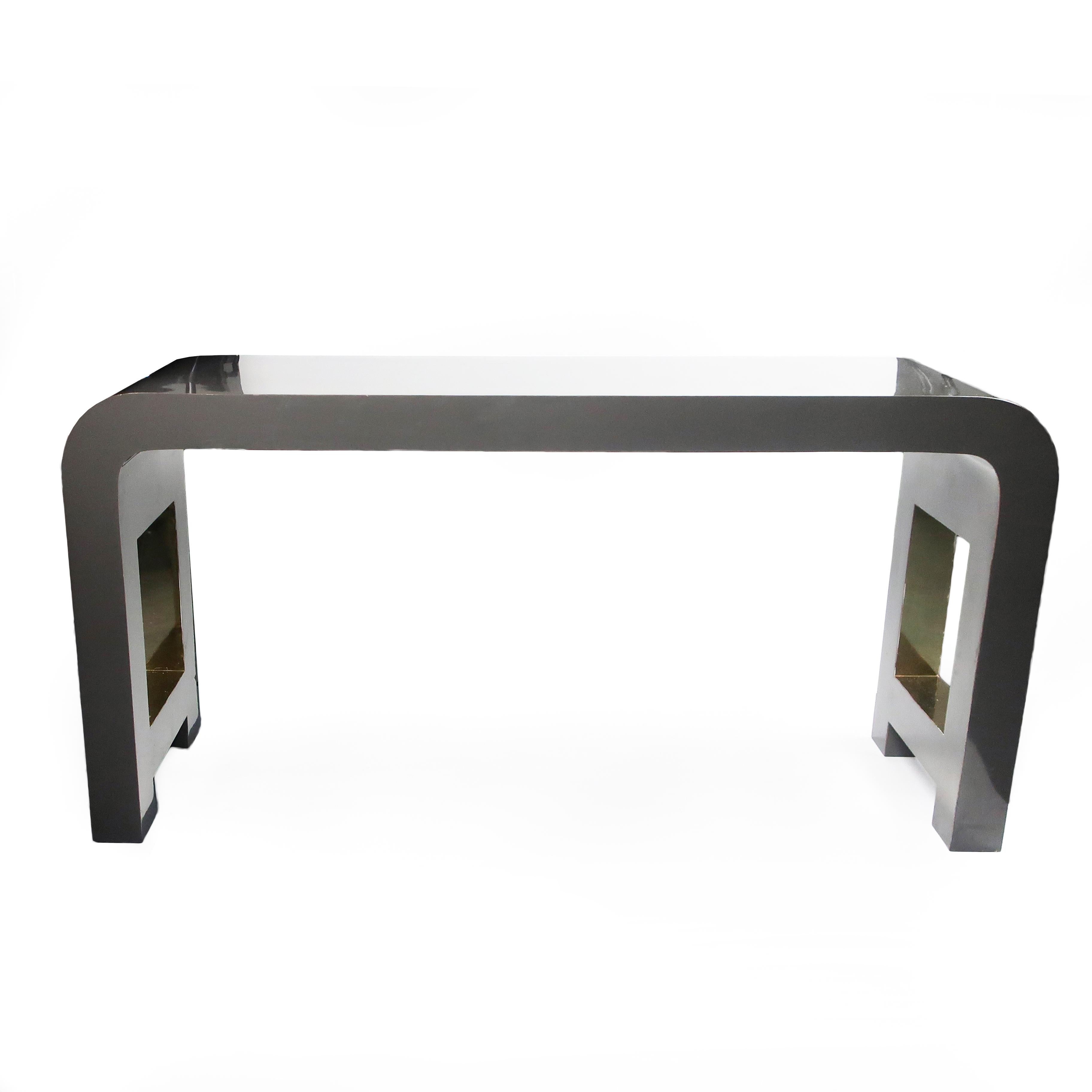 A vintage 1980s Postmodern waterfall console table in dark gray laminate with brass metallic laminate insets on cut out sides. Perfect for an entryway, behind a sofa, or as a desk in a bedroom or small apartment.

In good vintage condition with